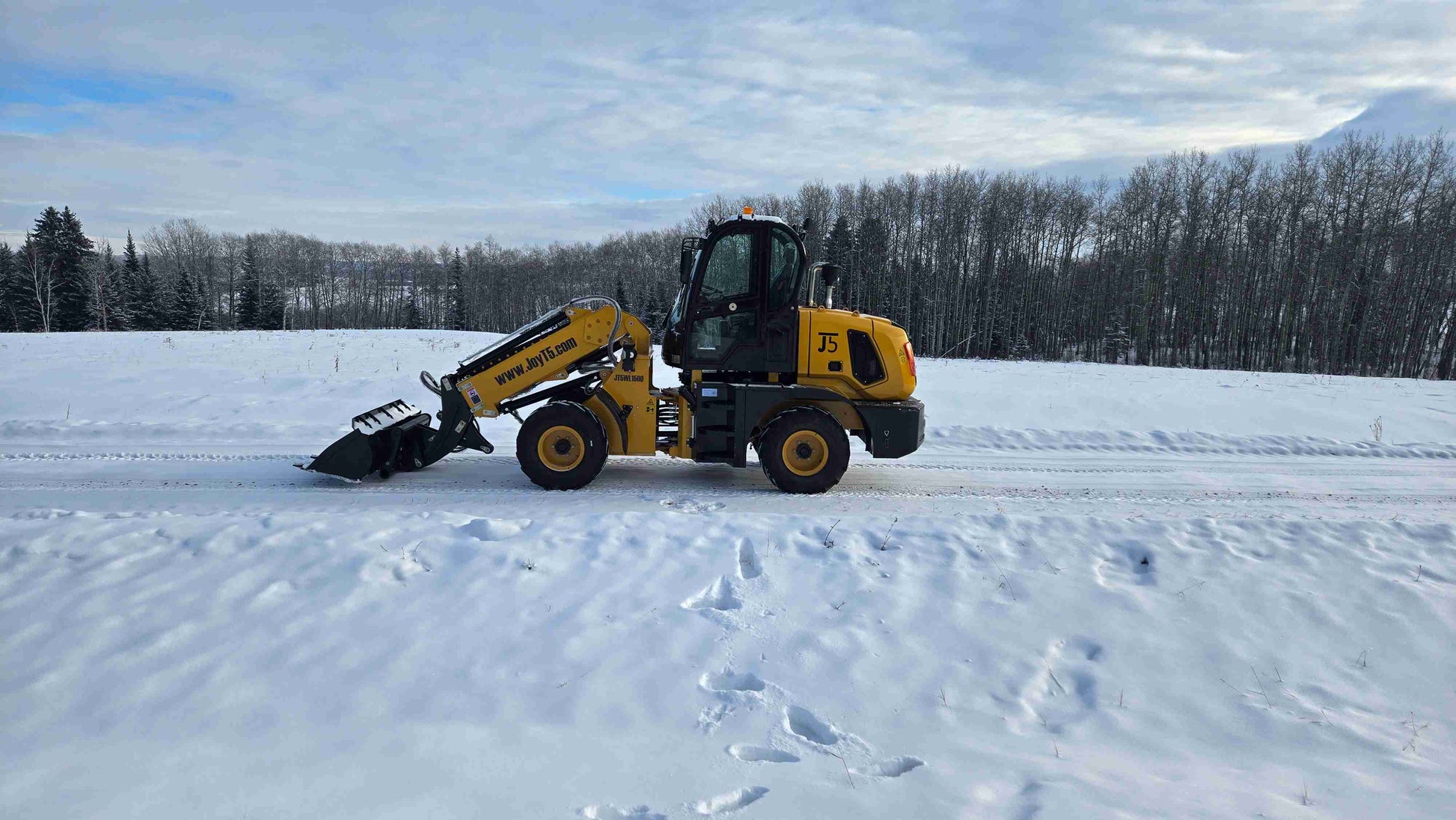 JT5WL1500 compact wheel loader 1.5 ton 3300 lbs side profile working on snow in Canada – heavy duty loader for construction and landscaping.