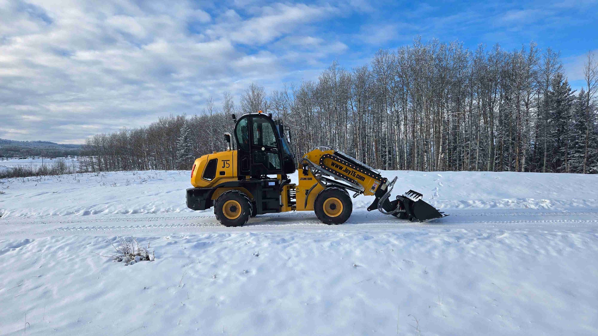 JT5WL1500 compact wheel loader 1.5 ton 3300 lbs side view with bucket down in snowy Canada – small loader for construction and material handling.