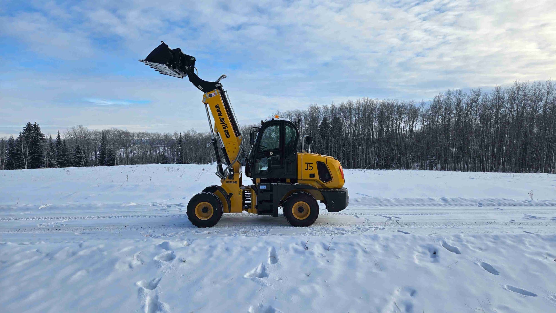 JT5WL1500 compact wheel loader 1.5 ton (3300 lbs) with raised bucket, side view in snowy Canada construction site.