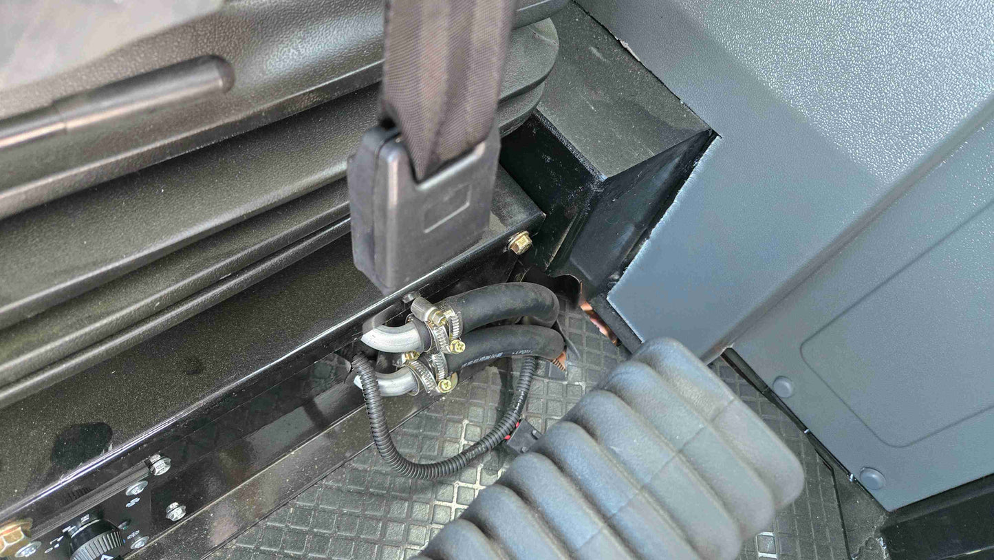 Close-up of JT5WL1500 compact wheel loader cabin showing seat belt lock, secure hydraulic hoses, and pedal with anti-slip floor design.