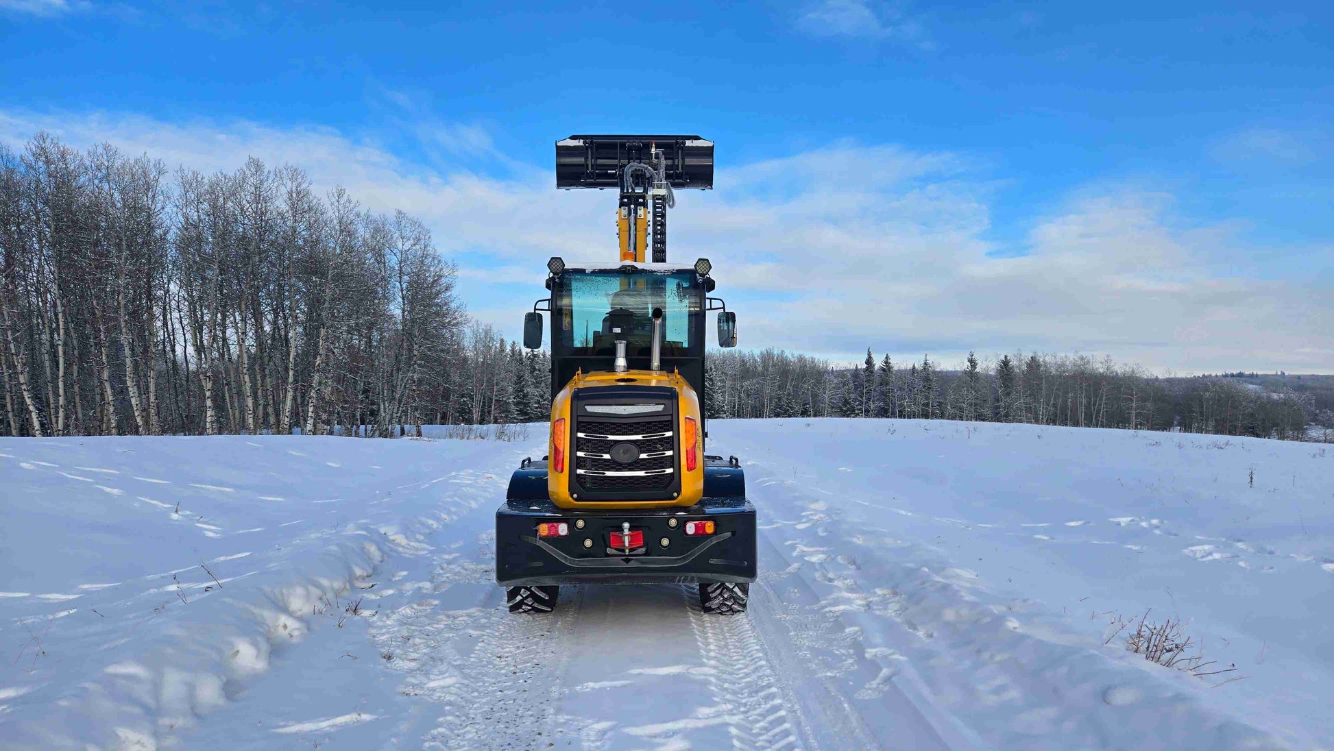 JT5WL1500 compact wheel loader rear view with bucket lifted upright on snowy road.