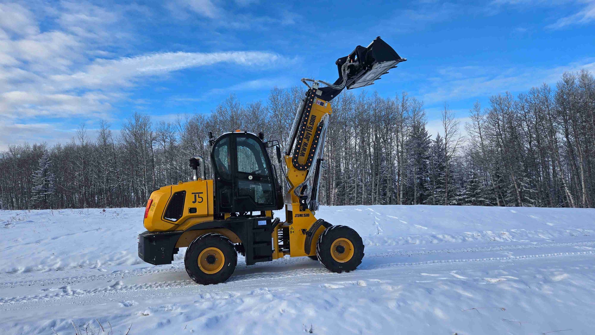JT5WL1500 compact wheel loader side profile with bucket lifted upright in snowy Canadian field.