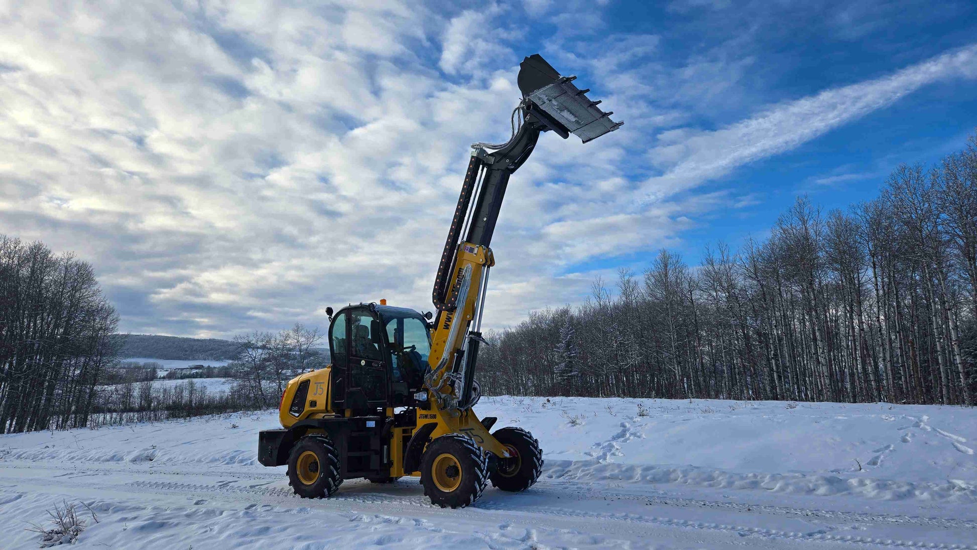 JT5WL1500 compact wheel loader side view with fully extended boom and tilted bucket in snowy outdoor environment.