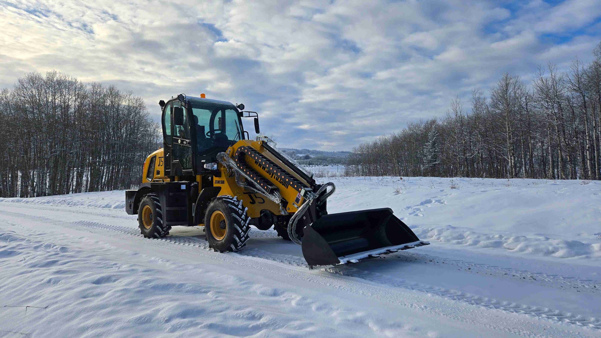 JT5WL1500 wheel loader side-front view with lowered bucket on snowy road.