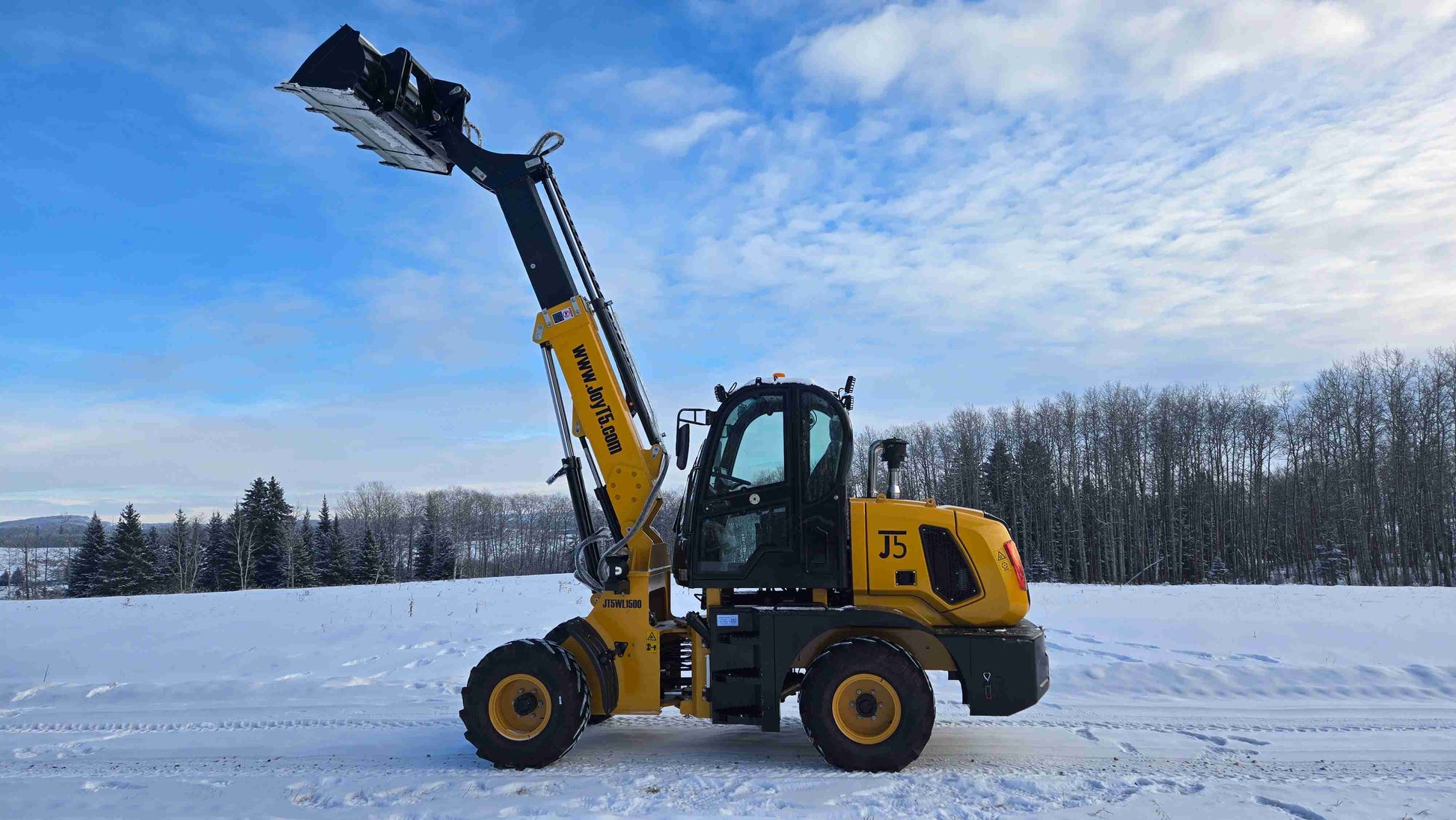 JT5WL1500 wheel loader side profile with raised boom and bucket in a snowy field.