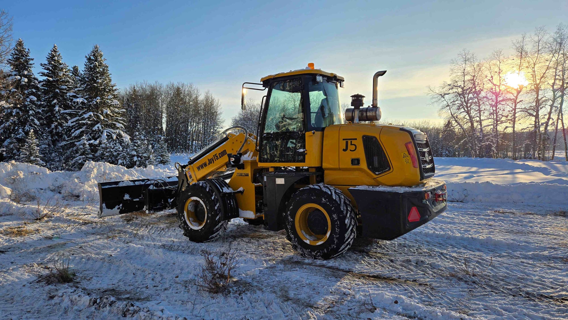 JT5WL2500 compact wheel loader clearing snow in Canada during winter sunset, efficient mini loader for construction and landscaping.