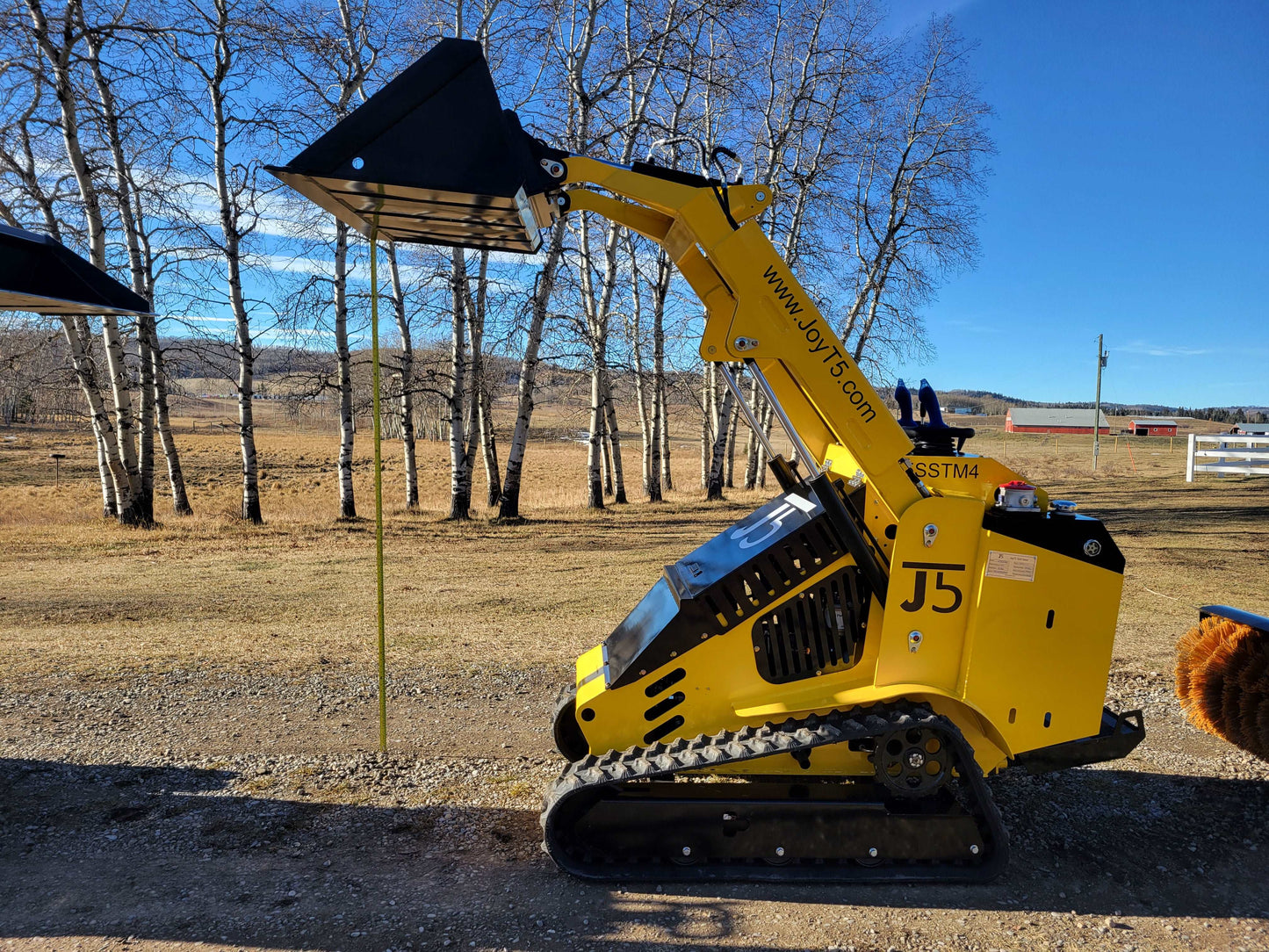 JoyT5 JT5SSTM4 compact tracked mini skid steer loader with raised bucket, diesel-powered machine for construction, landscaping, and farming.
