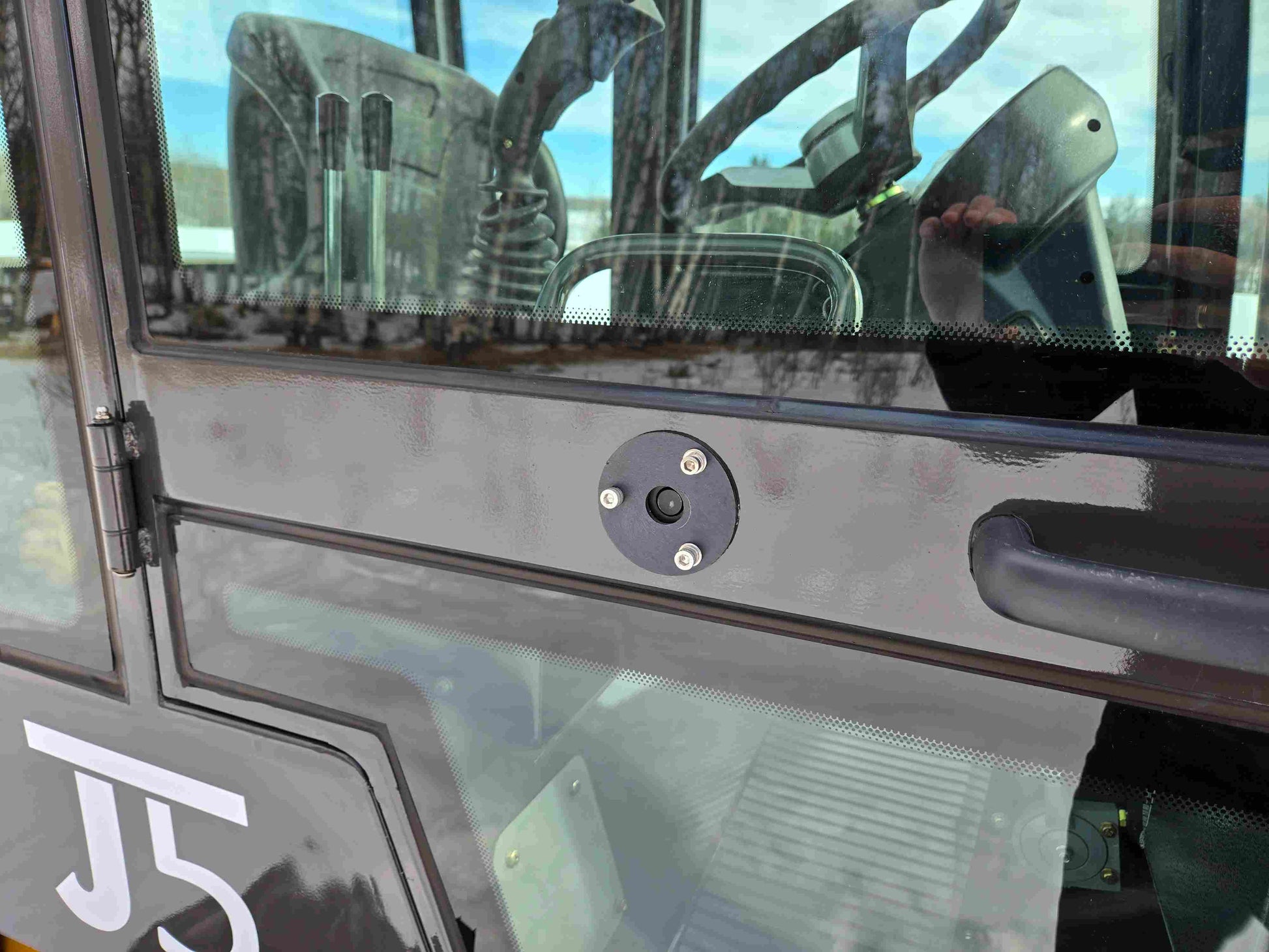 Close-up view of JT5 wheel loader cabin door locking mechanism and handle.
