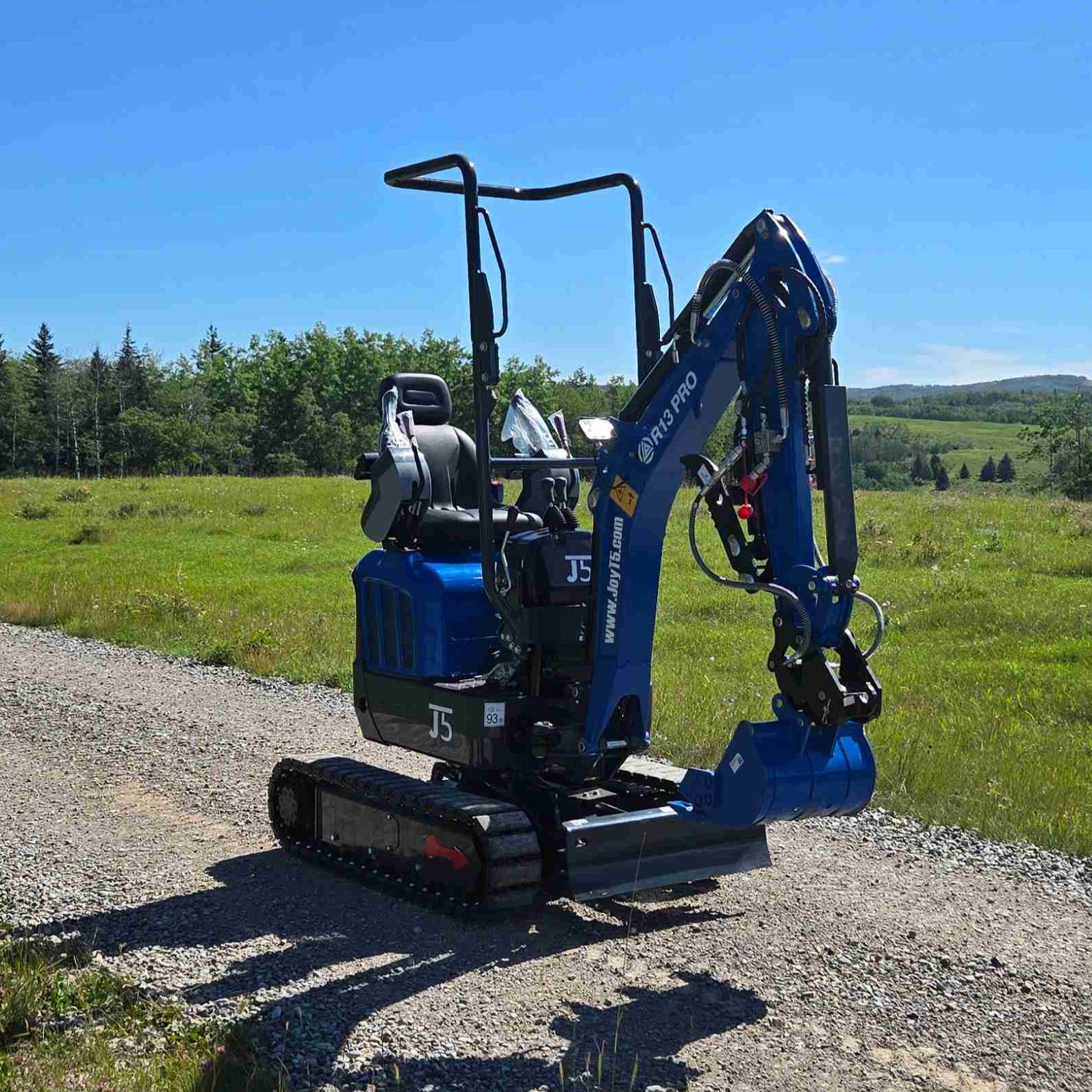 Rippa R13 mini excavator for sale by JoyT5 on a gravel road with a clear blue sky and green fields in the background