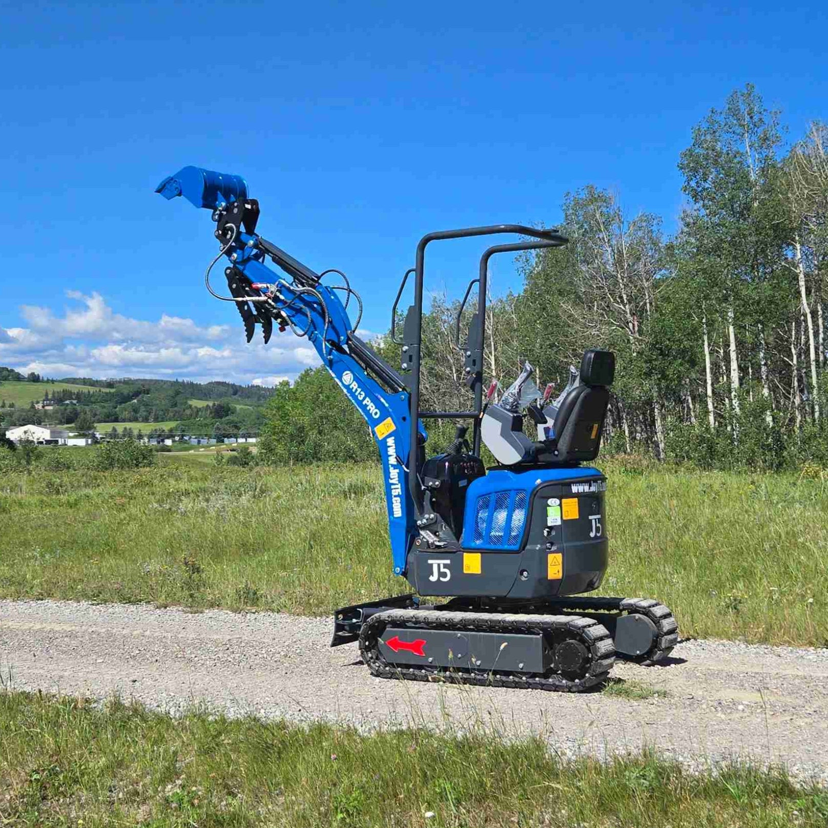 Rippa R13 mini excavator for sale by JoyT5 on a dirt road with trees and blue sky in the background