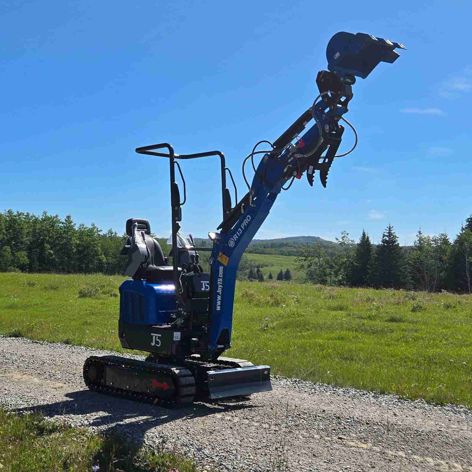 Rippa R13 mini excavator for sale by JoyT5 on a gravel road with a clear blue sky and green fields in the background
