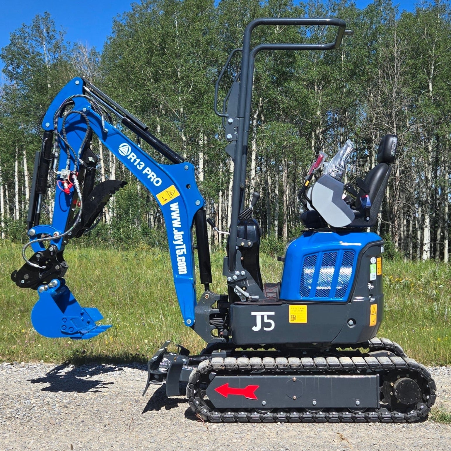 Rippa R13 mini excavator for sale by JoyT5 with attachments on a paved surface with trees in the background