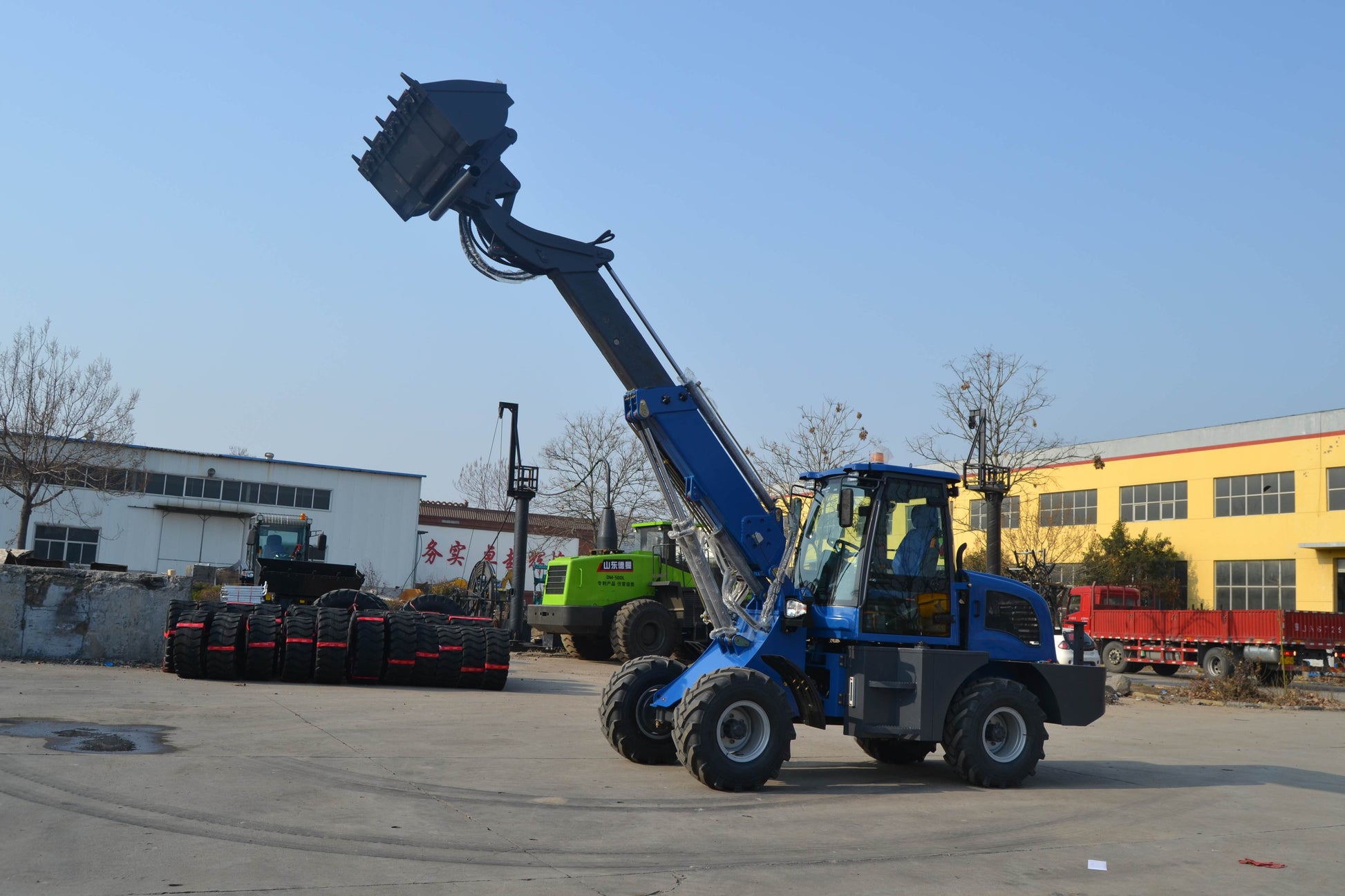 Blue wheel loader with raised telescopic boom and large bucket for heavy lifting tasks