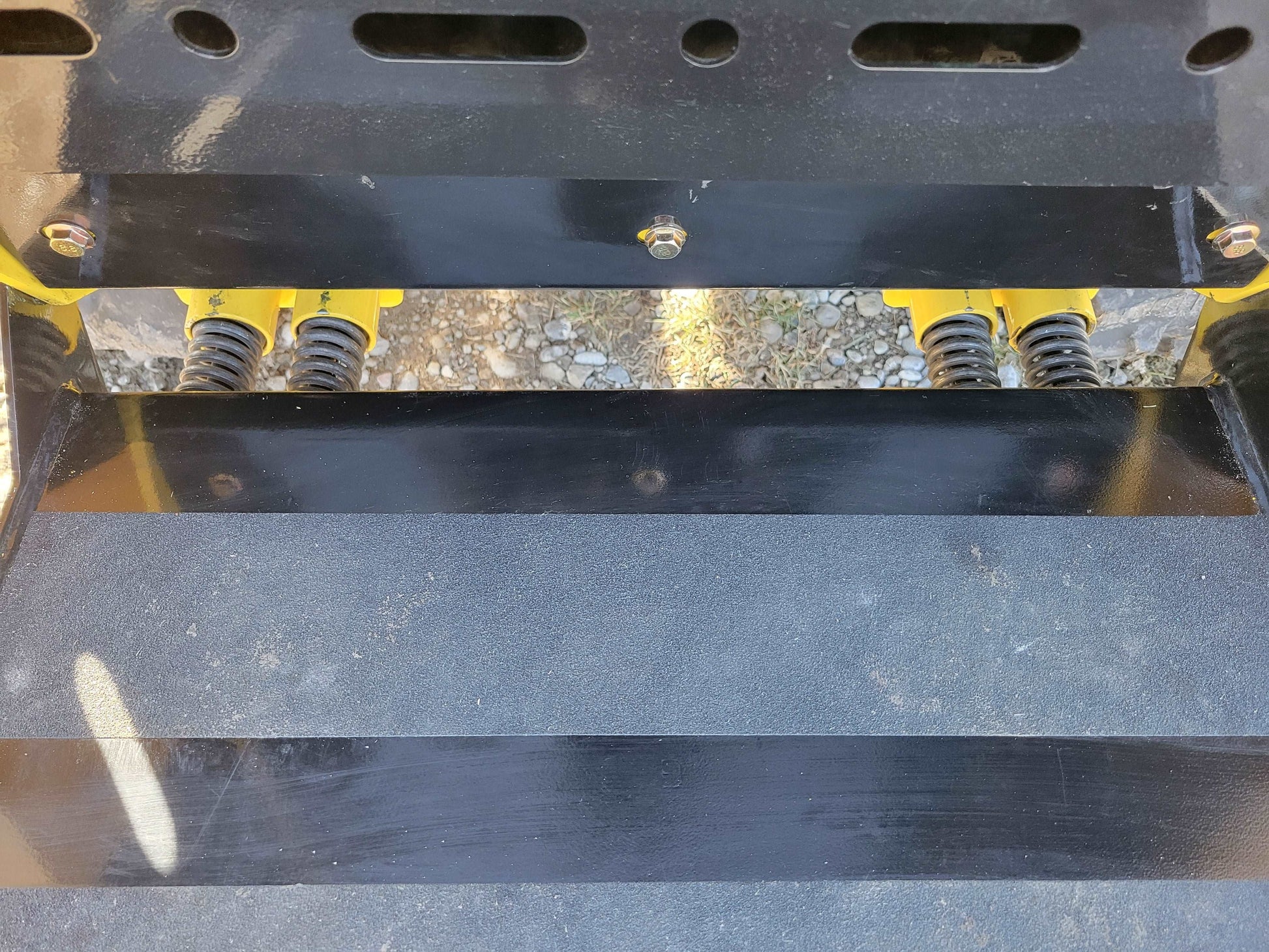 Close up of bucket attachment plate and spring mechanism on diesel tracked mini skid steer 25 HP loader in Canada showing durable construction for landscaping and building work


