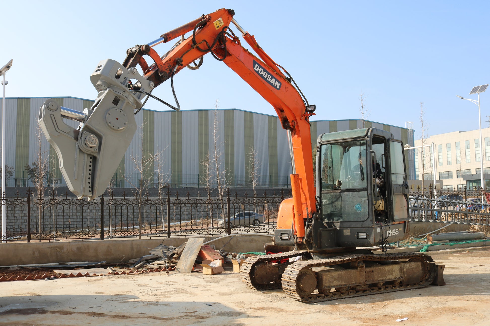Doosan excavator equipped with a heavy-duty hydraulic demolition shear at a construction site.
