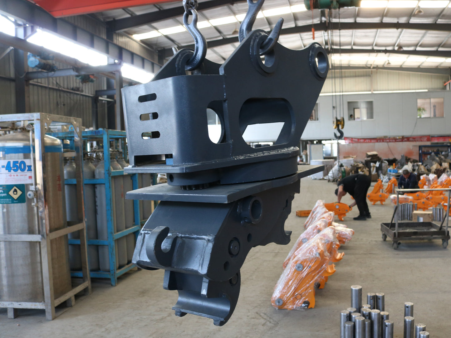 Excavator quick hitch for sale in Canada hydraulic coupler attachment lifted by crane inside manufacturing facility showing durable construction equipment quality and design
