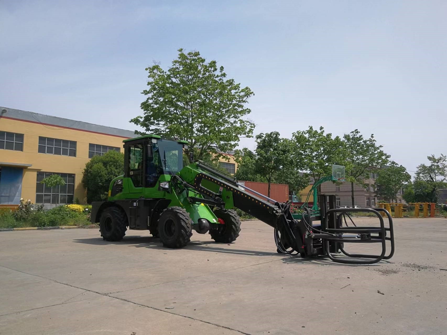 Green wheel loader with bale grapple attachment for handling hay, silage, and round bales in agriculture