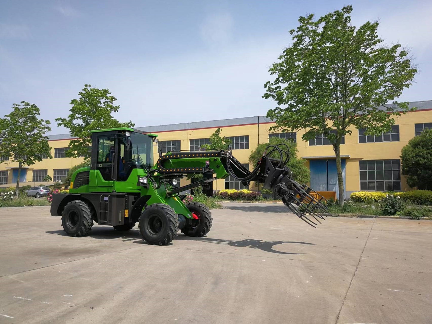 Green wheel loader equipped with log grapple attachment for handling timber and forestry work