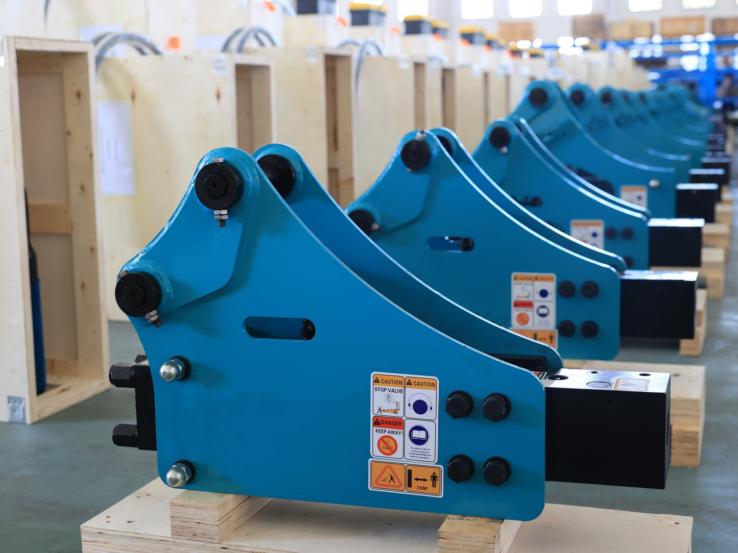 Hydraulic breaker hammer for excavators Canada and USA showing blue heavy duty breaker attachments aligned on pallets in factory ready for demolition and construction applications.

