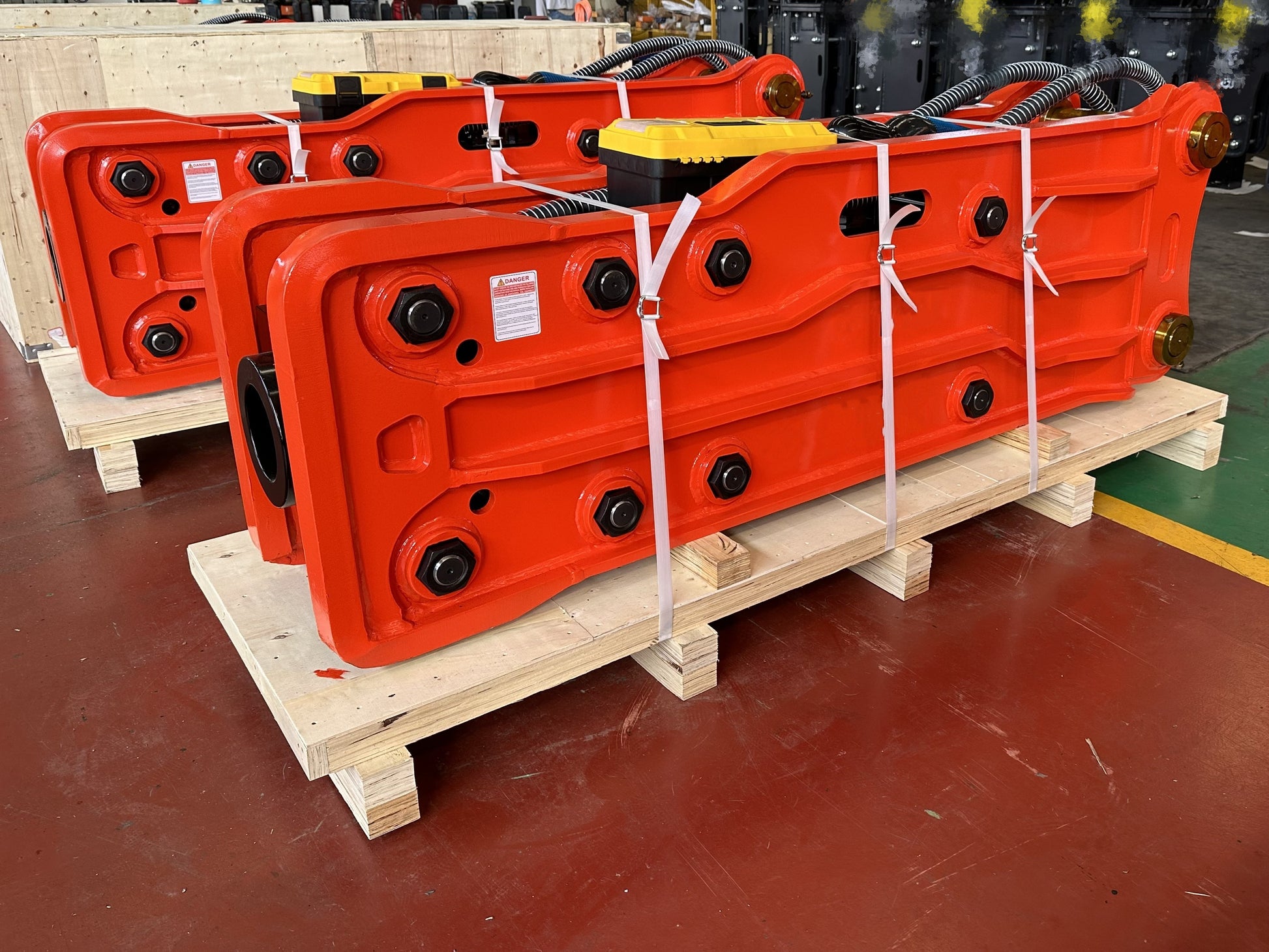 Hydraulic breaker hammer for excavators Canada and USA showing red heavy duty breaker attachments strapped on pallets ready for delivery to construction and demolition projects.