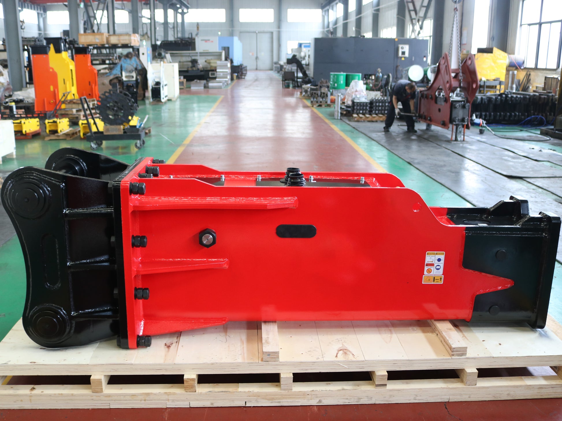 Hydraulic breaker hammer for excavators Canada and USA showing red heavy duty breaker attachment on pallet inside workshop ready for demolition and construction use.