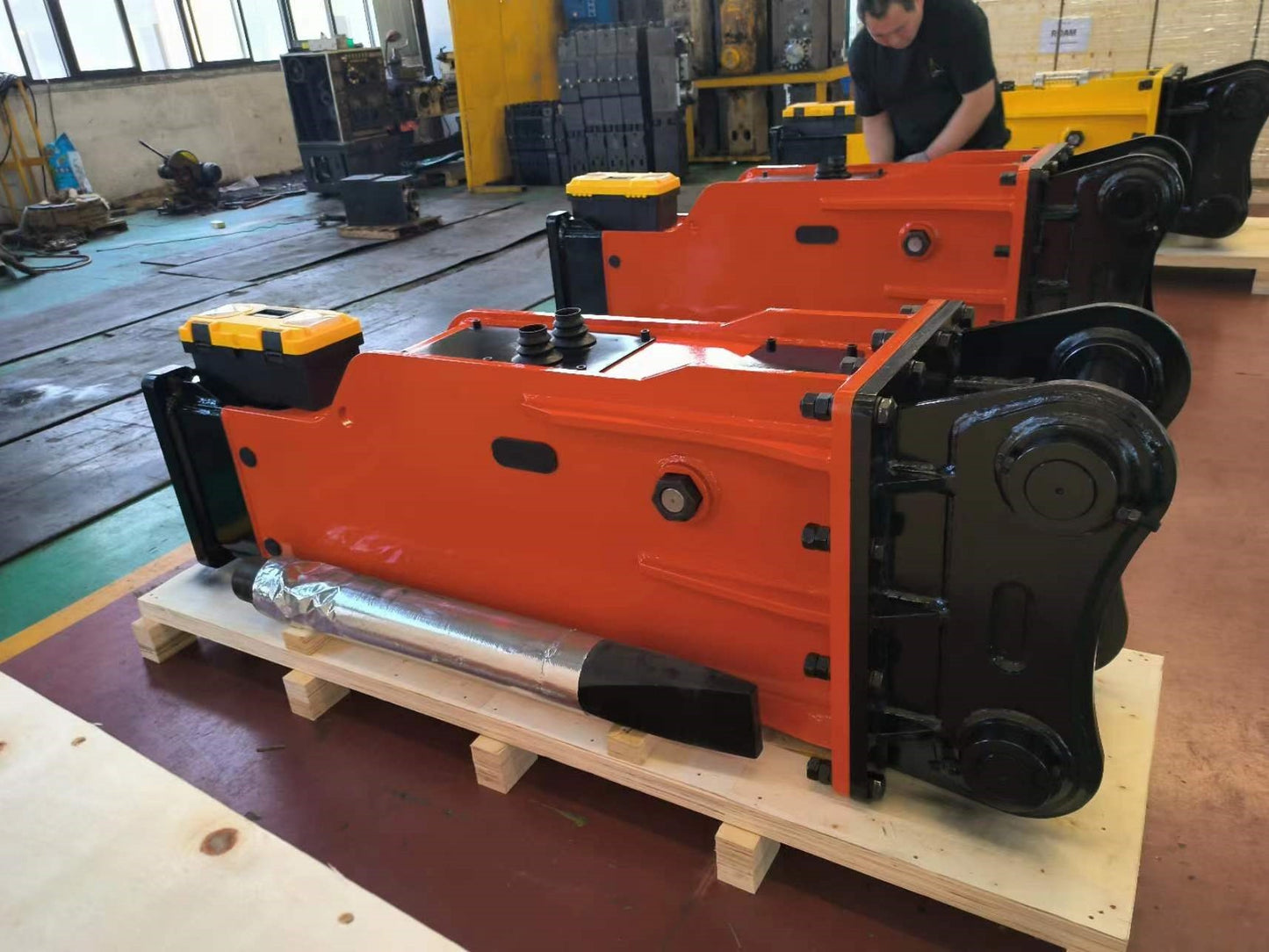 Hydraulic breaker hammer for excavators Canada and USA showing red heavy duty breaker attachments on pallets in factory ready for demolition and construction work.


