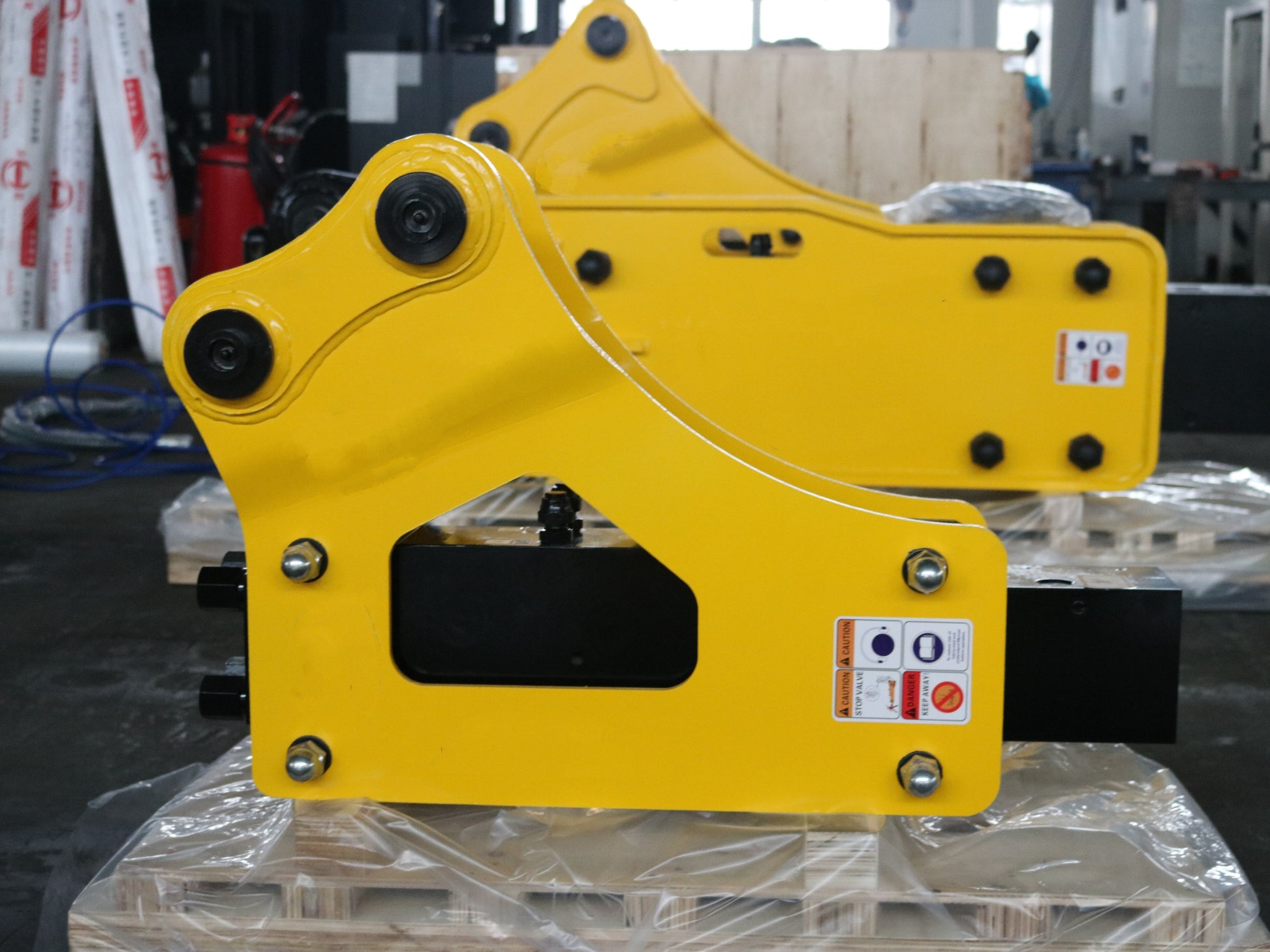 Hydraulic breaker hammer for excavators Canada and USA showing yellow heavy duty breaker attachments on pallets in factory ready for demolition and construction equipment use.