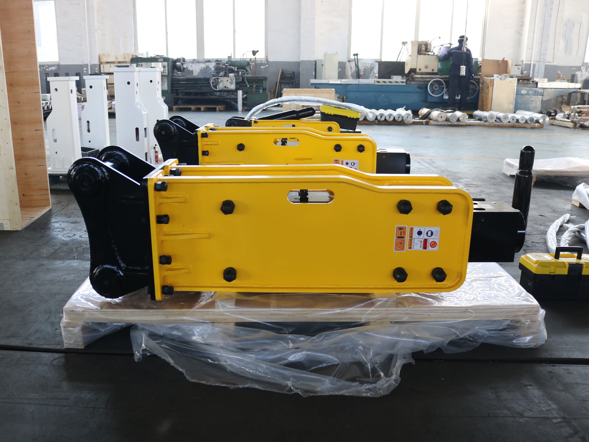 Hydraulic breaker hammer for excavators Canada and USA showing multiple yellow heavy duty breaker attachments on pallets ready for construction and demolition work.


