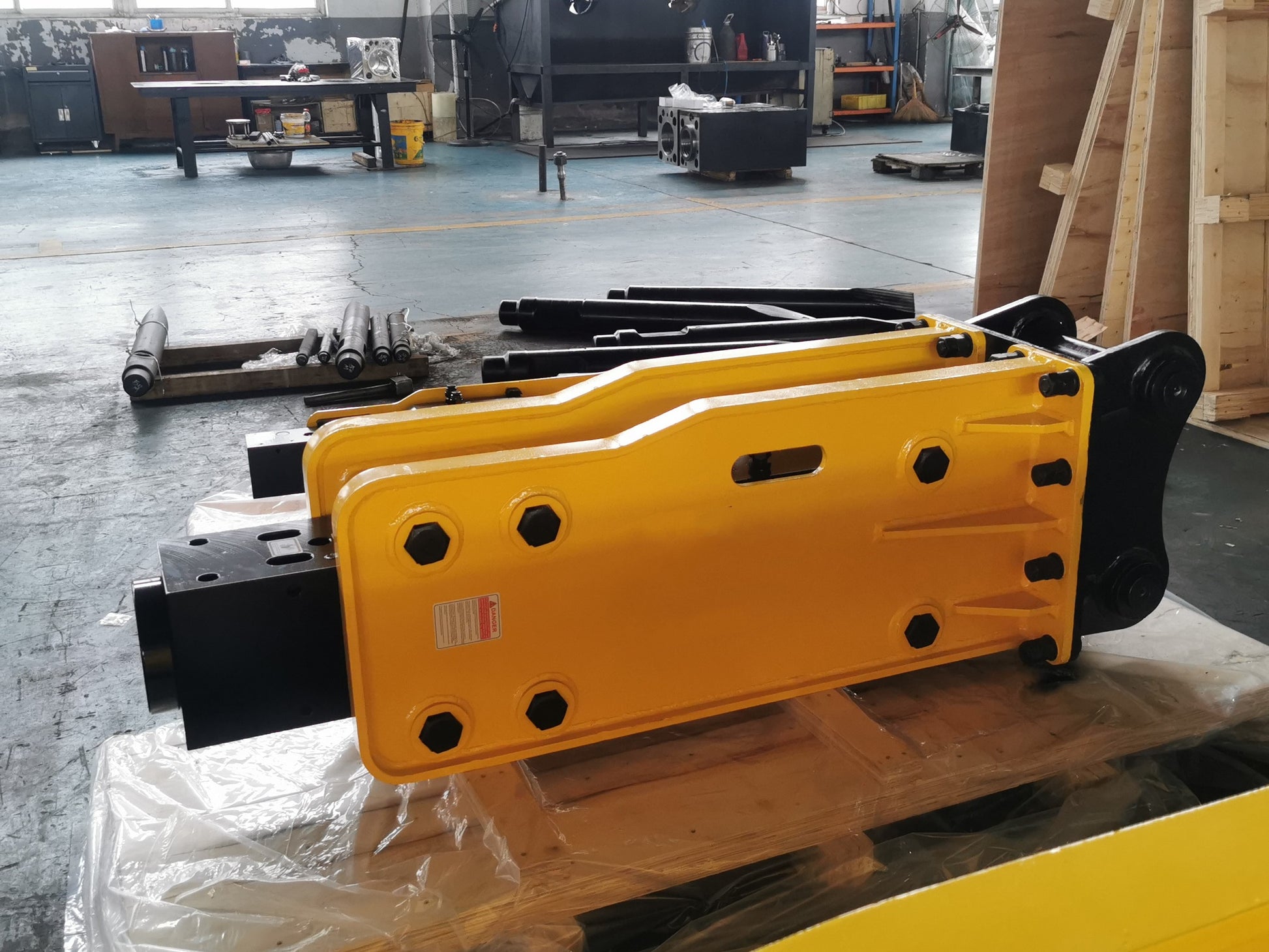 Hydraulic breaker hammer for excavators Canada and USA showing yellow heavy duty breaker attachment in factory ready for demolition and construction equipment use.

