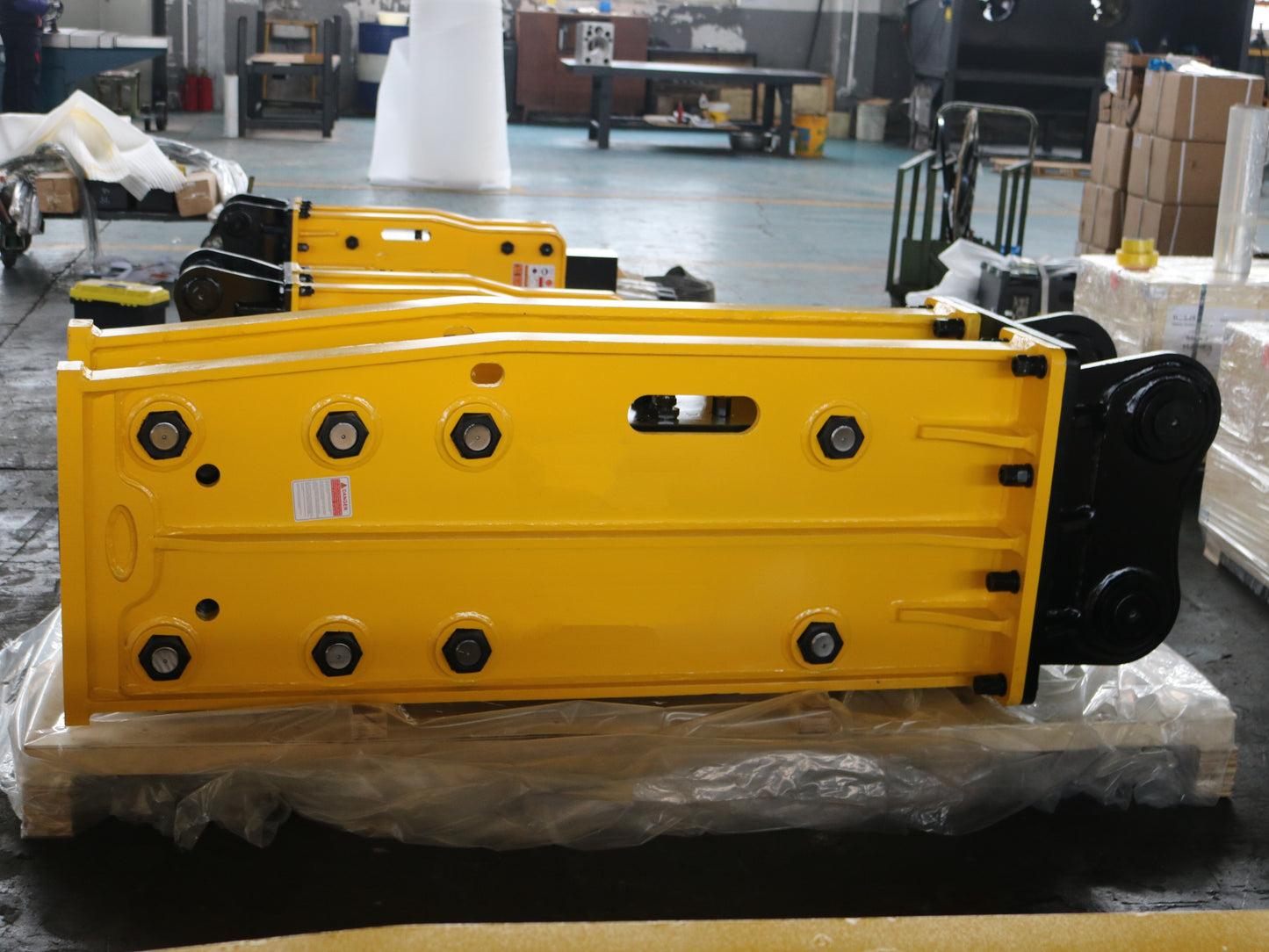 Hydraulic breaker hammer for excavators Canada and USA showing yellow heavy duty breaker tool on pallet inside factory ready for demolition and construction use.
