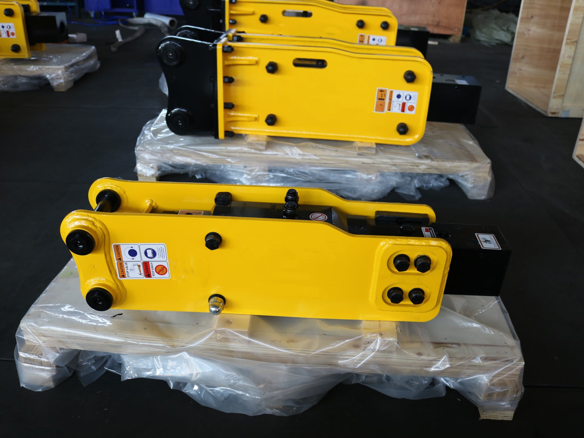 Hydraulic breaker hammer for excavators Canada and USA showing yellow heavy duty breaker attachments on pallets ready for shipment used in demolition and construction projects.

