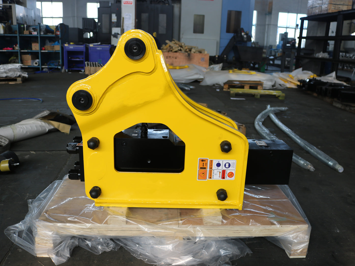 Hydraulic breaker hammer for excavators Canada and USA showing yellow heavy duty breaker tool on pallet inside factory ready for demolition and construction attachment use.


