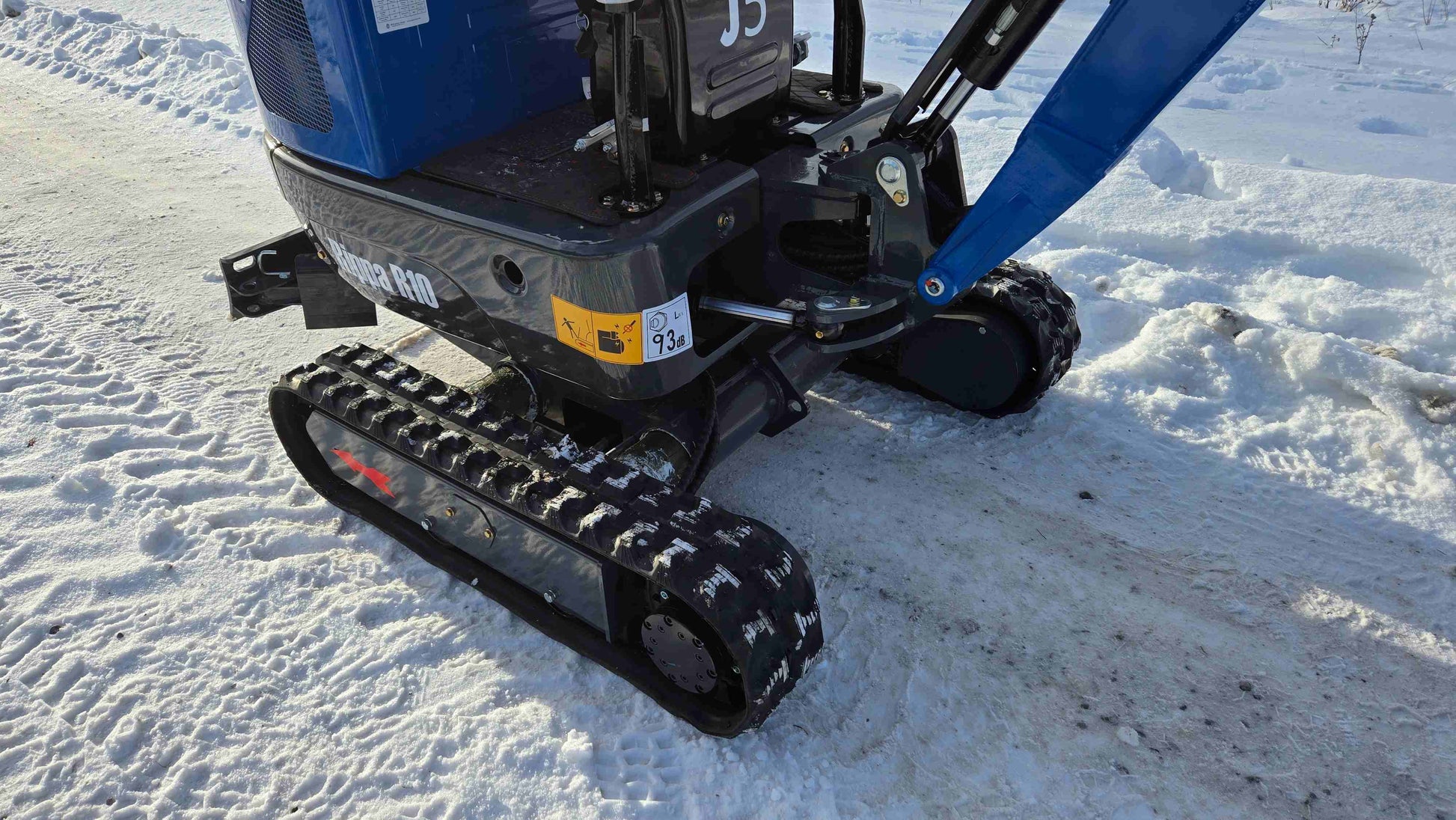 Rippa R10 mini excavator parked on snow showing the rubber tracks undercarriage and blade in Canada from JoyT5