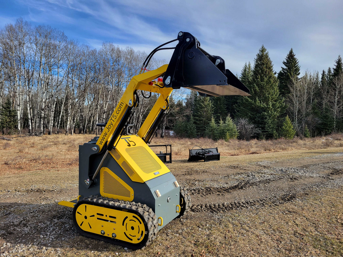 JoyT5 JT5SSTM3 compact mini skid steer loader side view with raised bucket, tracked skid steer for landscaping, material handling, and construction.