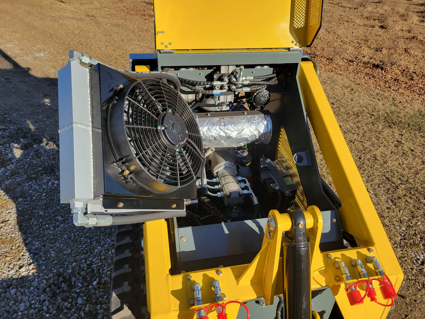 Engine compartment of JoyT5 JT5SSTM3 mini skid steer loader showing cooling fan, hydraulic pump, and battery placement