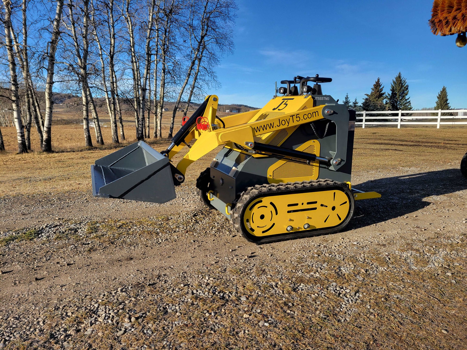 JoyT5 JT5SSTM3 mini skid steer with bucket attachment working on gravel path | compact track loader for landscaping and construction tasks