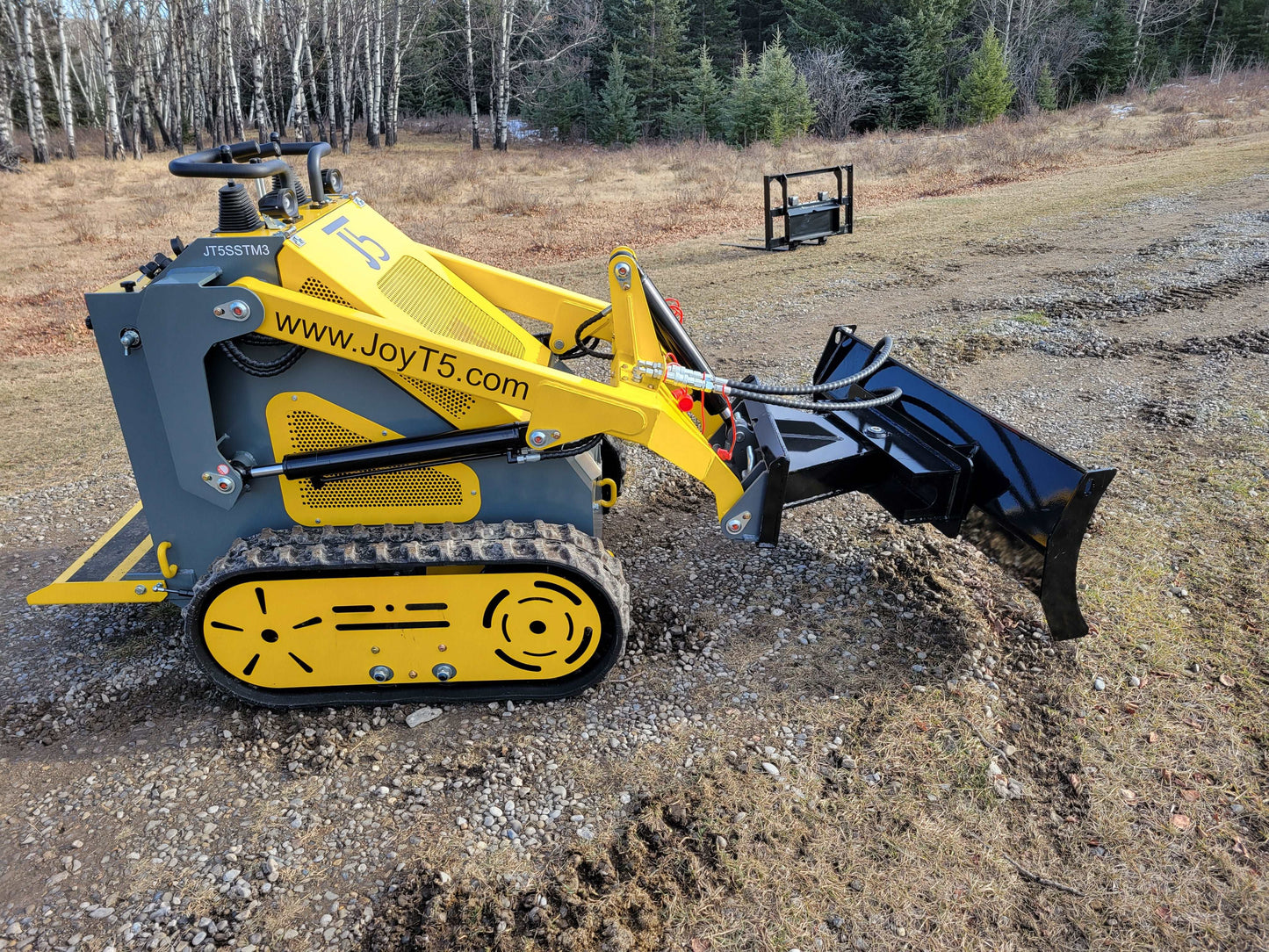 JoyT5 JT5SSTM3 mini tracked skid steer using grading blade attachment on a Canada outdoor worksite