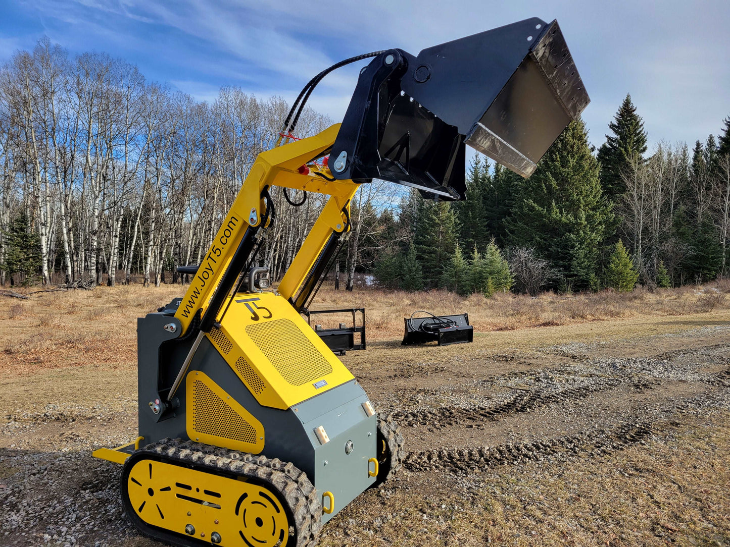 JoyT5 JT5SSTM3 mini tracked skid steer with raised front bucket showing lifting and dumping performance on a Canadian construction and landscaping site
