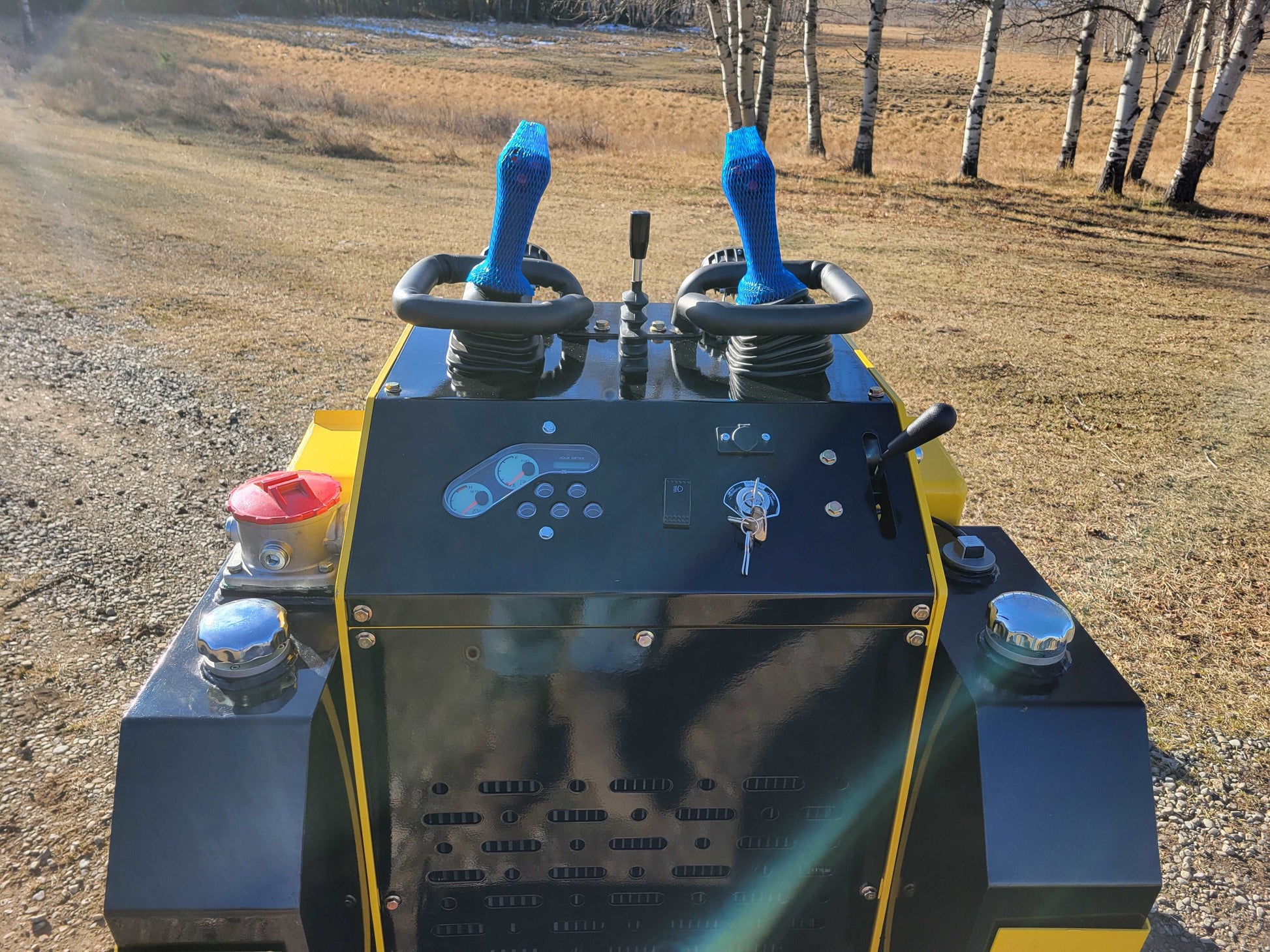 Close-up of JoyT5 JT5SSTM4 mini skid steer loader control panel with joystick controls and ignition key, compact diesel-powered tracked loader.