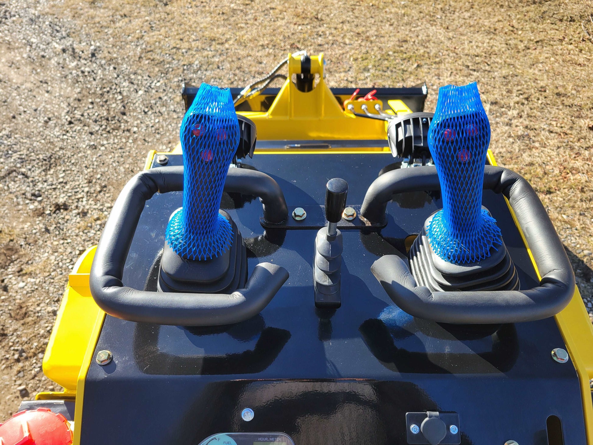 Close-up view of JoyT5 JT5SSTM4 mini skid steer loader dual joystick controls with protective mesh covers, designed for precision operation.