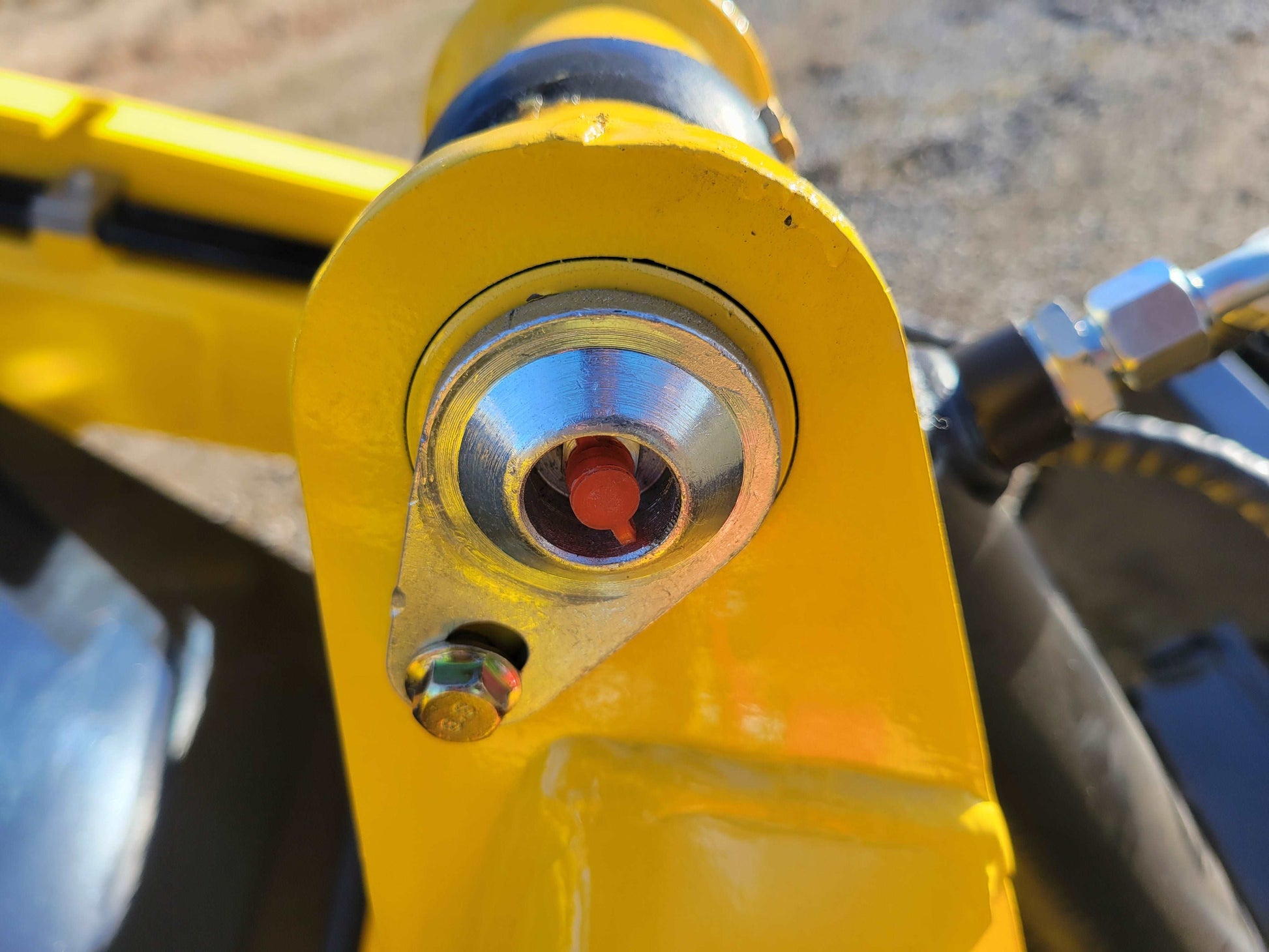 Close-up of hydraulic oil sight glass with red fluid indicator mounted on the arm joint of the JoyT5 JT5SSTM4 mini skid steer.
