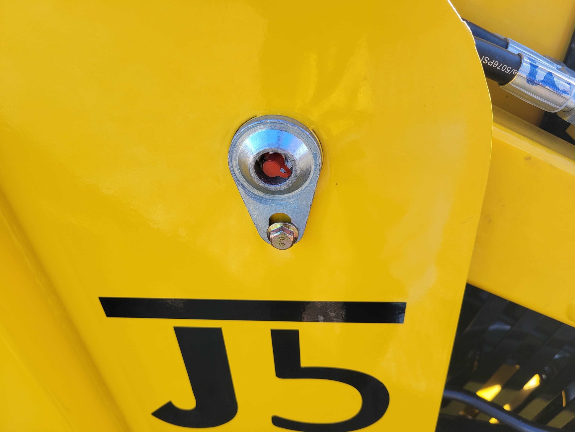 Close‑up of JoyT5 JT5SSTM4 mini skid 
steer hydraulic oil sight glass on yellow 
chassis  diesel tracked 25 HP Perkins 
engine loader with 400 kg lifting capacity for construction and landscaping in 
Canada.