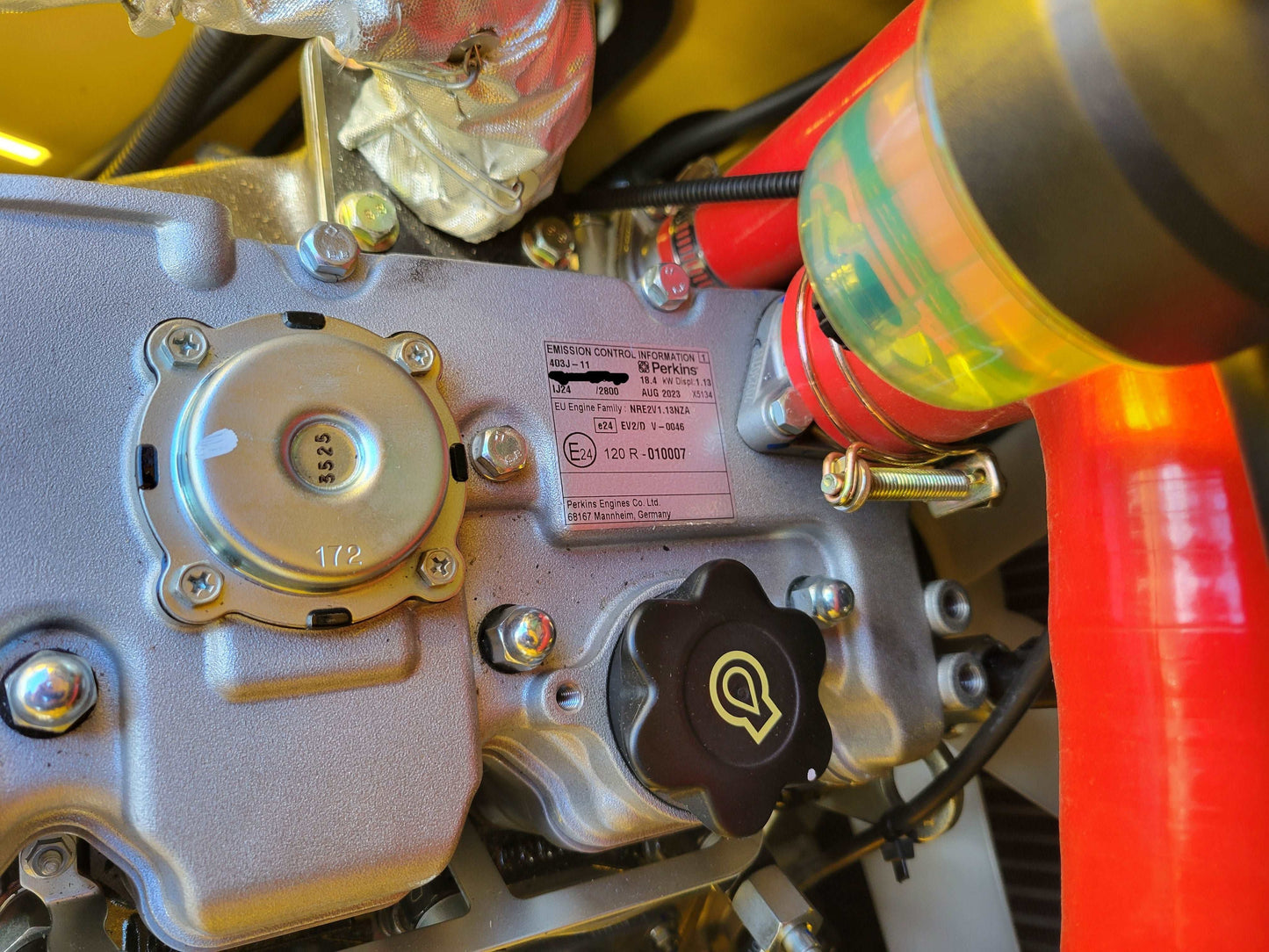 Perkins engine emission control plate, oil cap, and coolant hose in JoyT5 JT5SSTM4 mini skid steer engine compartment.
