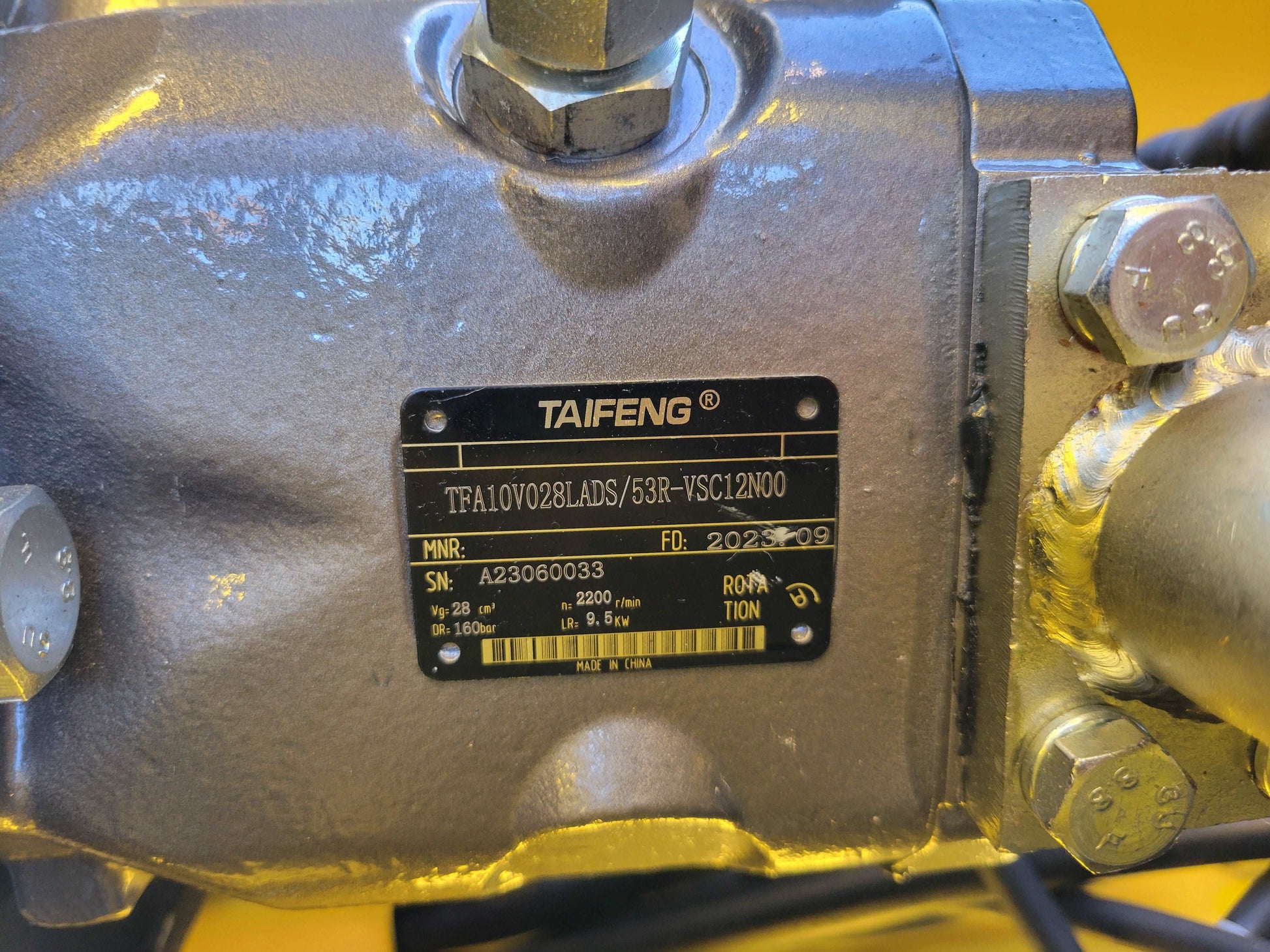Close-up of Taifeng hydraulic pump serial plate with specifications and manufacturing details on JoyT5 JT5SSTM4 mini skid steer.