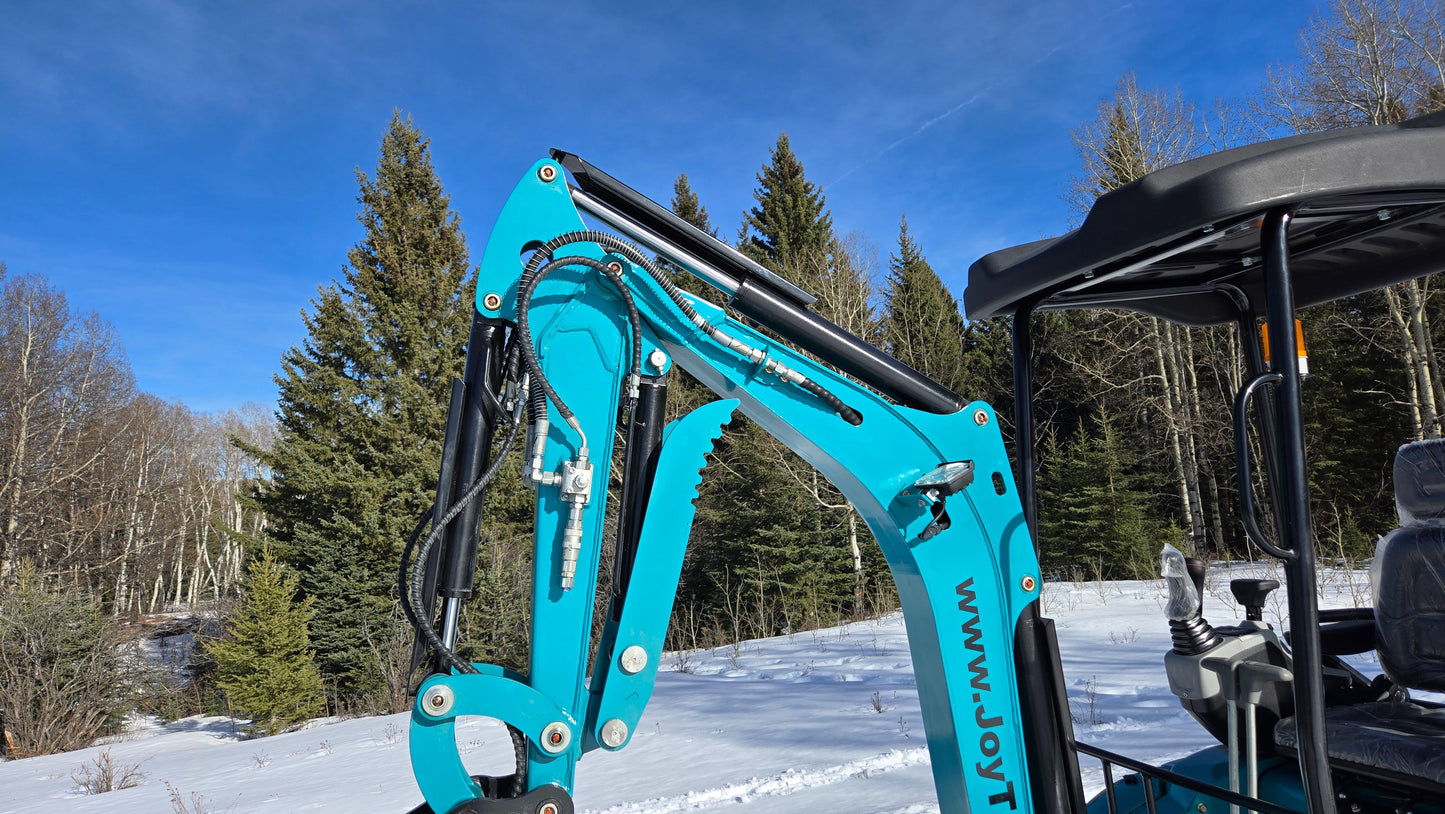 JoyT5 mini excavator boom and hydraulic lines with auxiliary couplers, next to operator cabin.
