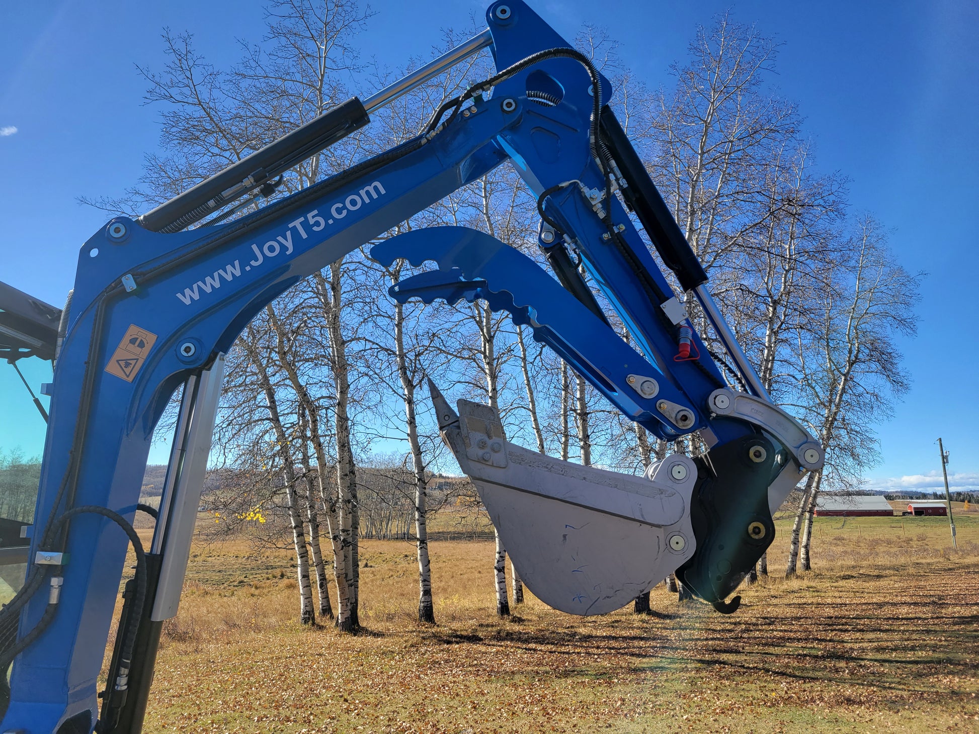 JoyT5 mini excavator bucket with hydraulic thumb working position beside trees in Canada construction field