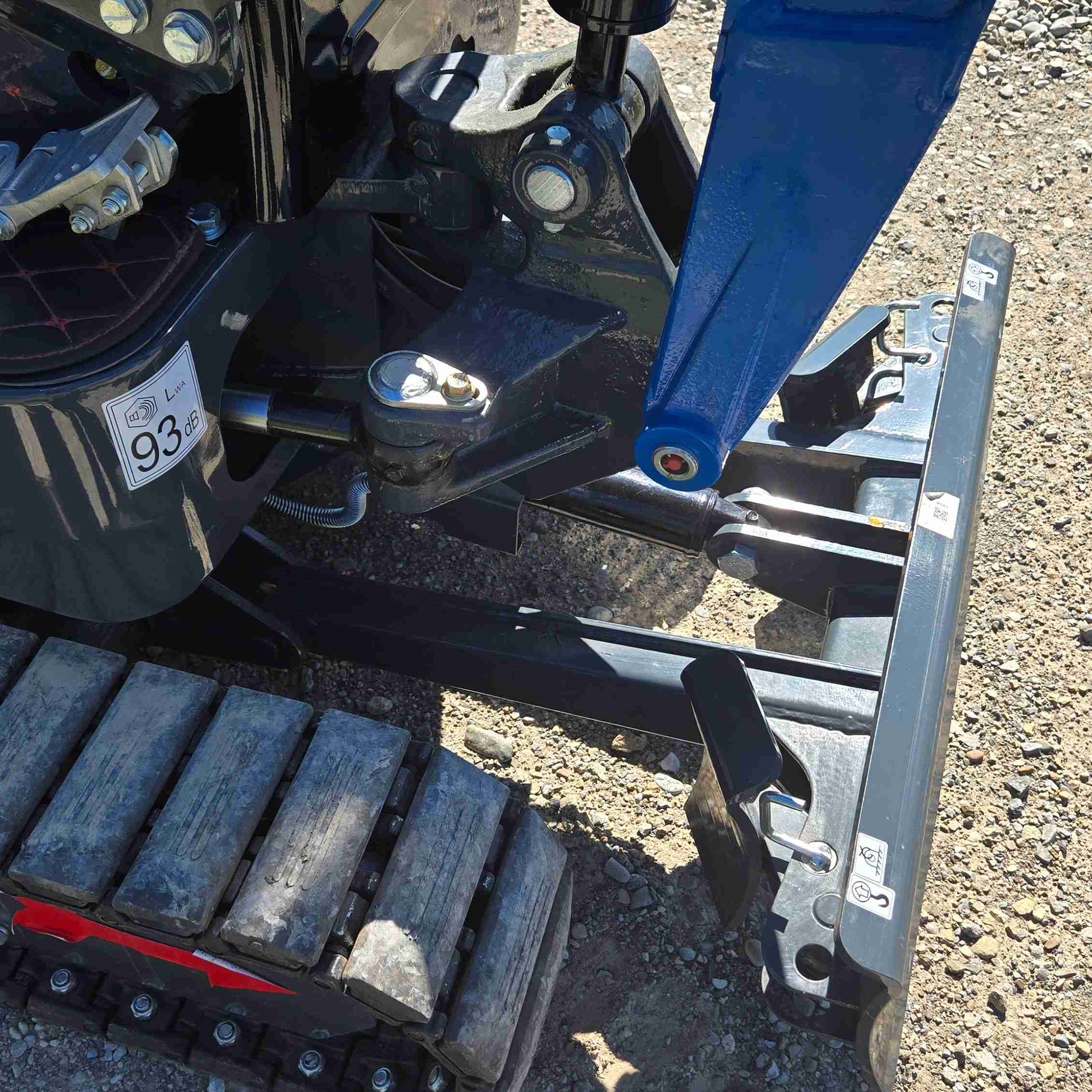 Side view close-up of JoyT5 mini excavator front dozer blade showing hydraulic linkage, pivot joint and rubber track system, engineered for precise grading, leveling and backfilling in construction and landscaping projects across Canada