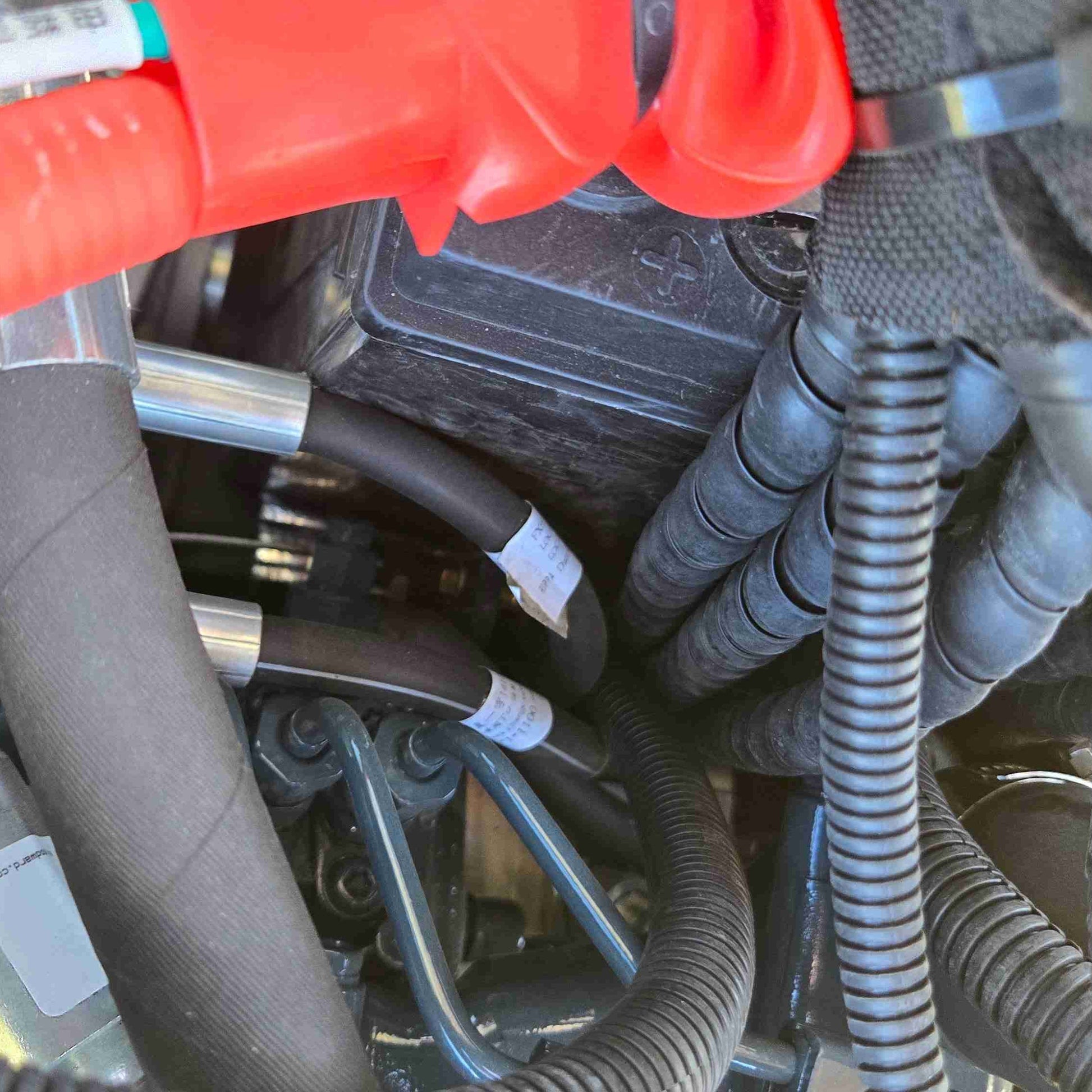 Close-up of JoyT5 mini excavator hydraulic hoses and protected wiring system, showing reinforced hose connections and durable cable protection for reliable performance in construction and landscaping work