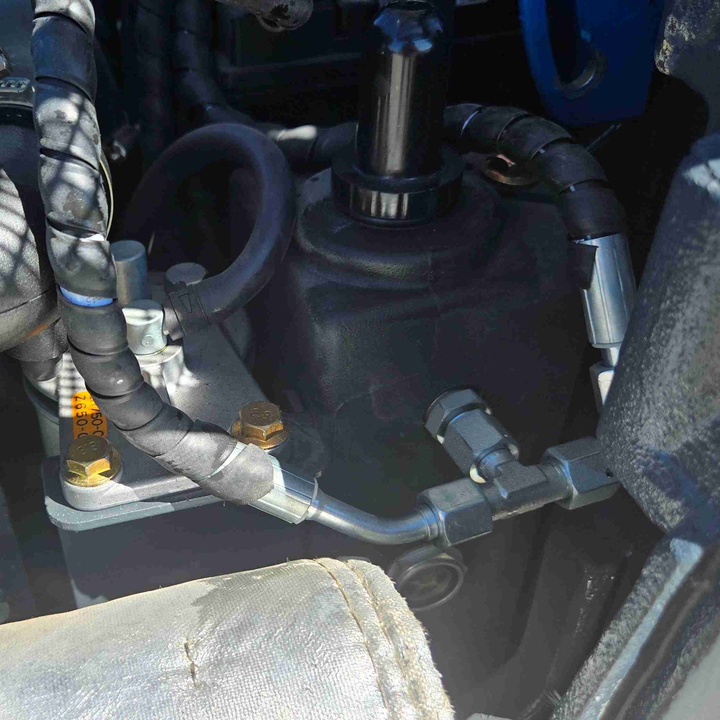 Close-up of JoyT5 mini excavator hydraulic motor and valve assembly with reinforced hoses and precision fittings, showcasing high-pressure hydraulic performance and durable construction