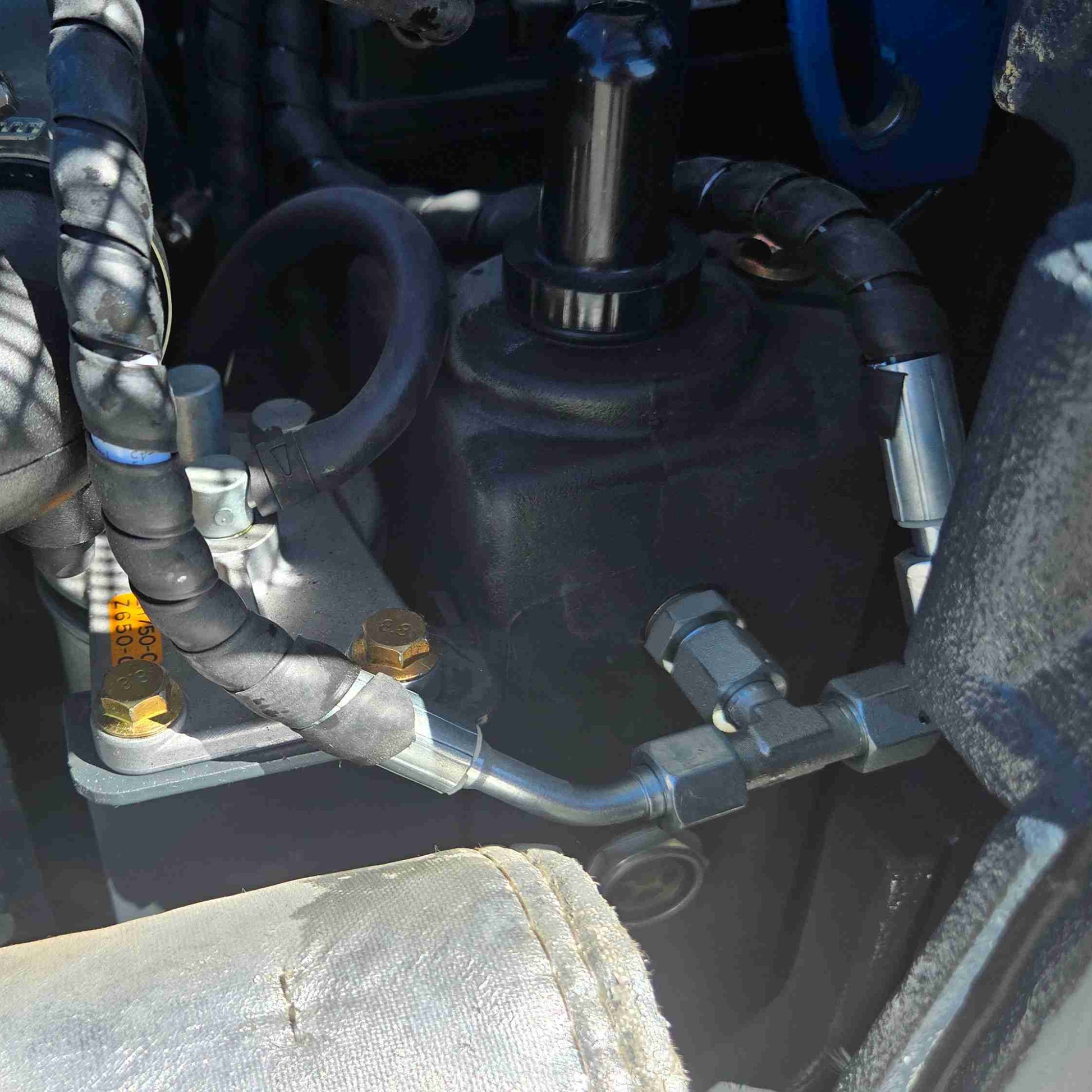 Close-up of JoyT5 mini excavator hydraulic motor and valve assembly with reinforced hoses and precision fittings, showcasing high-pressure hydraulic performance and durable construction